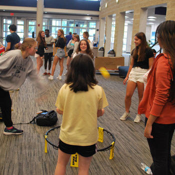 Five students standing in a circle playing a game
