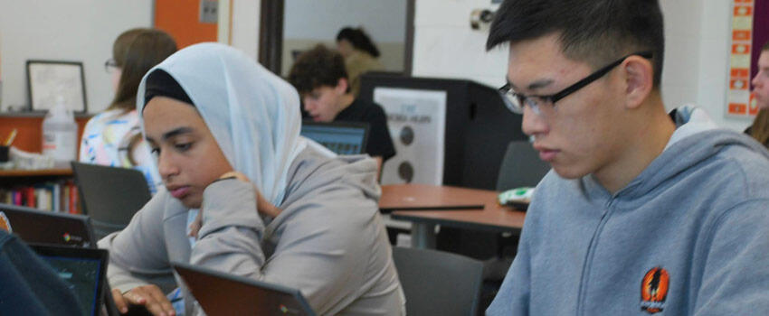 Two students working on Chromebooks in a classroom