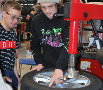 Students working on a tire in an autos class