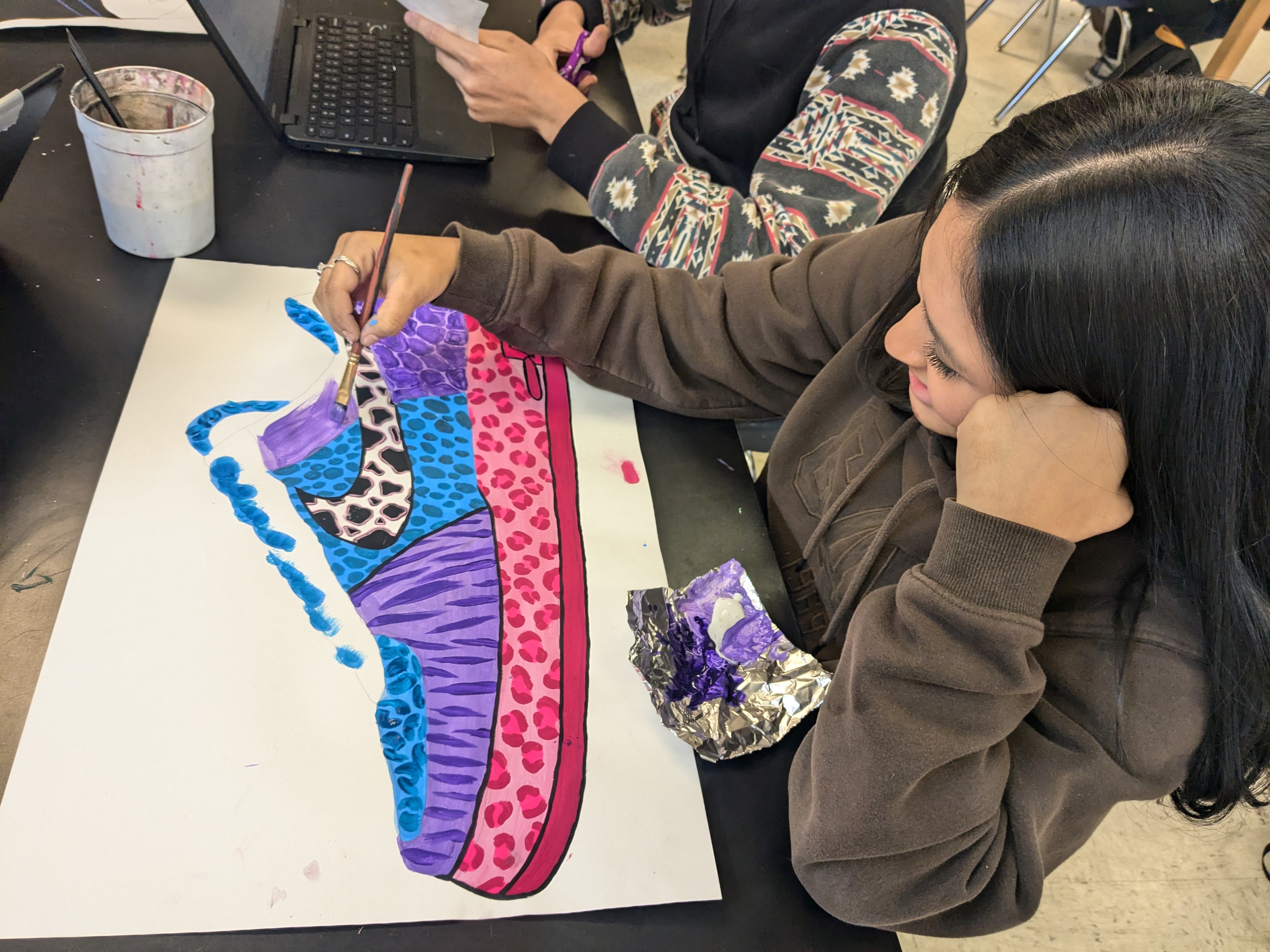 A West Rusk High School student painting a colorful tennis shoe in Art class
