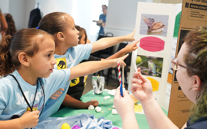 Two young girls interact with a vendor booth at STEMfest 2024.