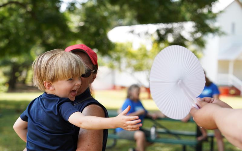 Young boy reaches for a paper fan at STEMfest 2024
