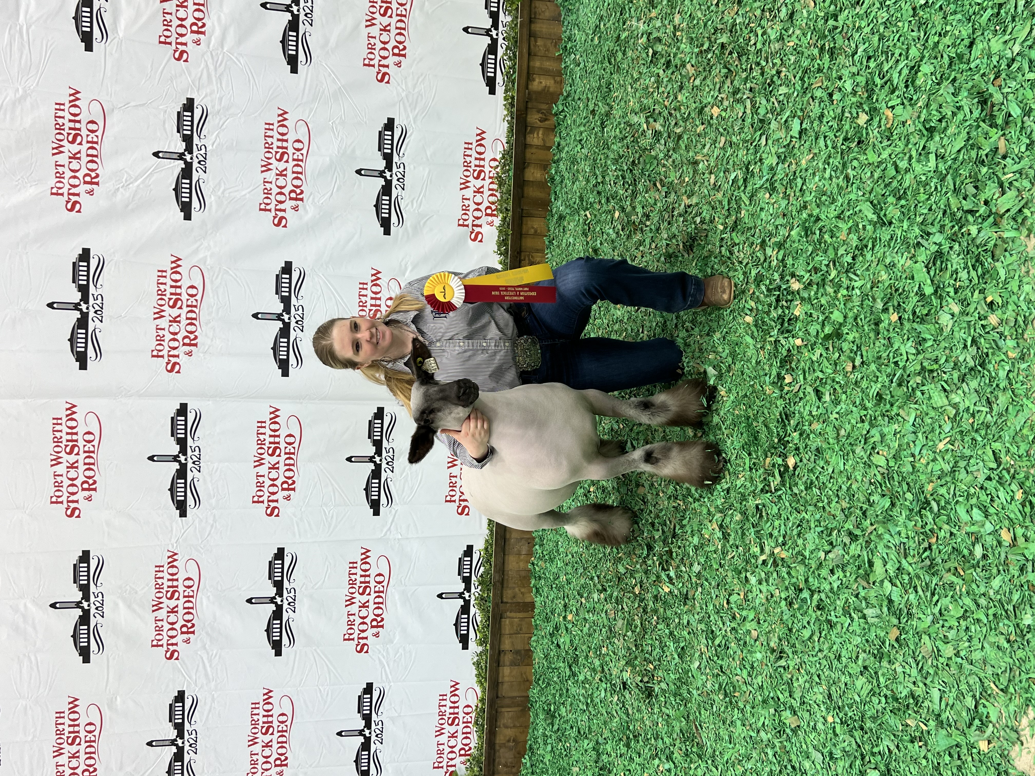 A girl standing kneeling next to a goat