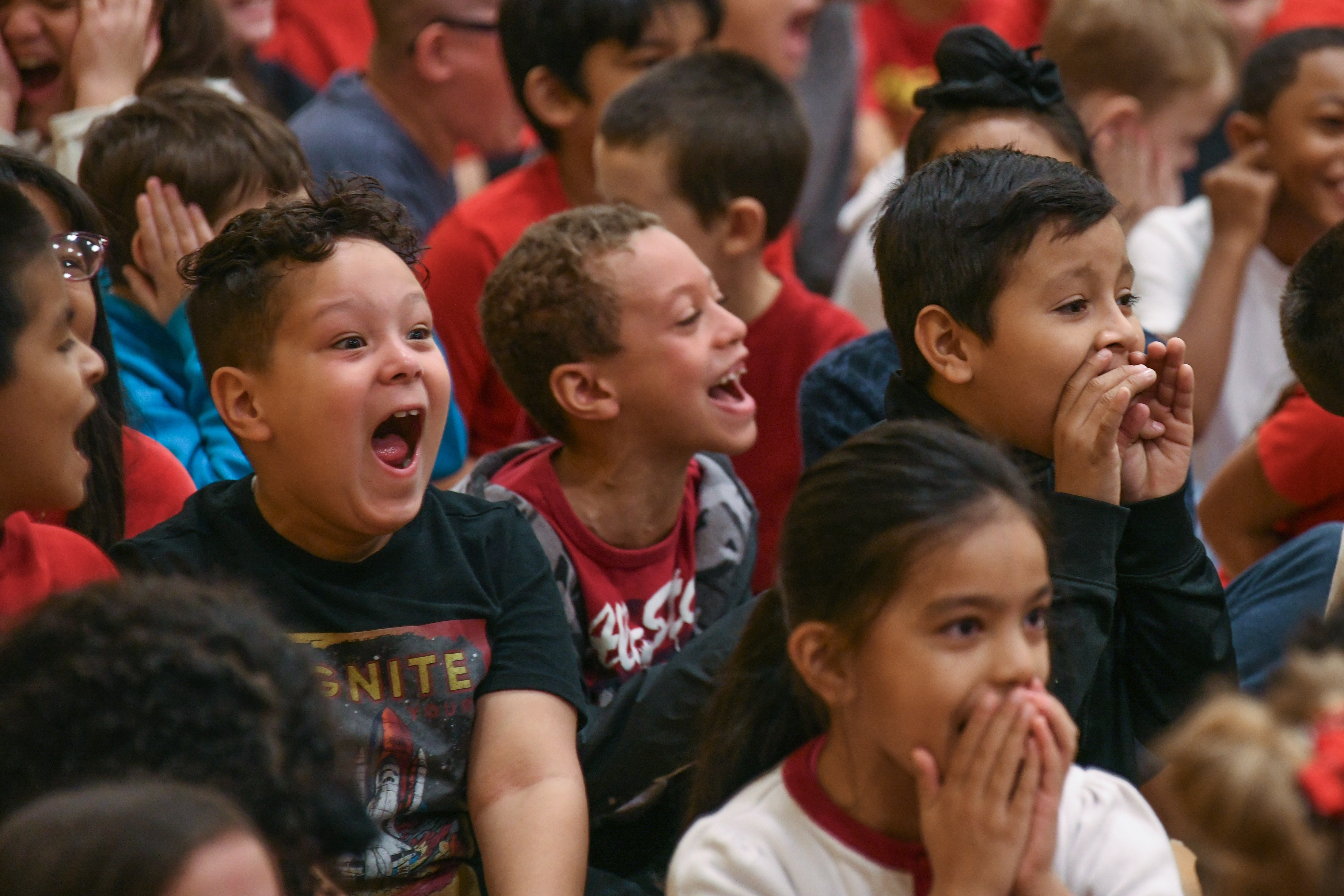 Students sit in a group, smiling and clapping.