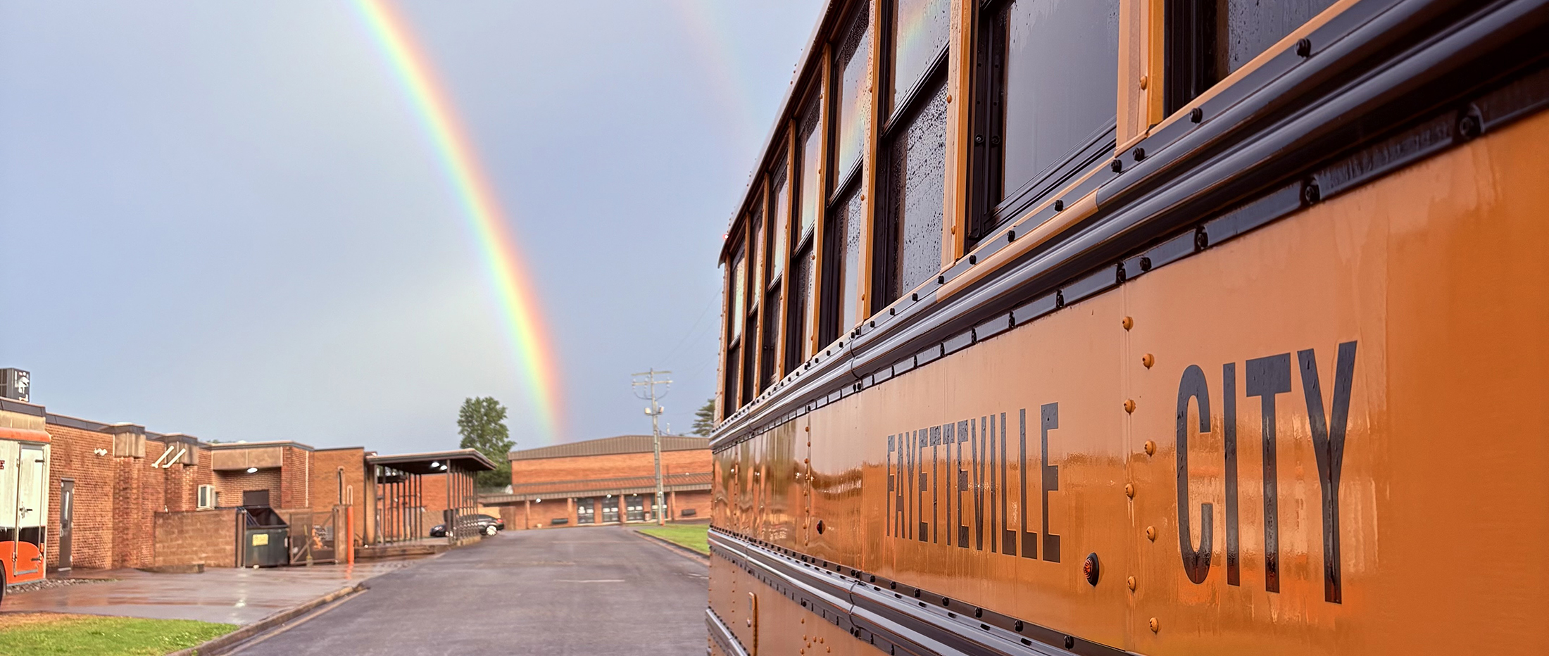 Double rainbow over school campus by school bus