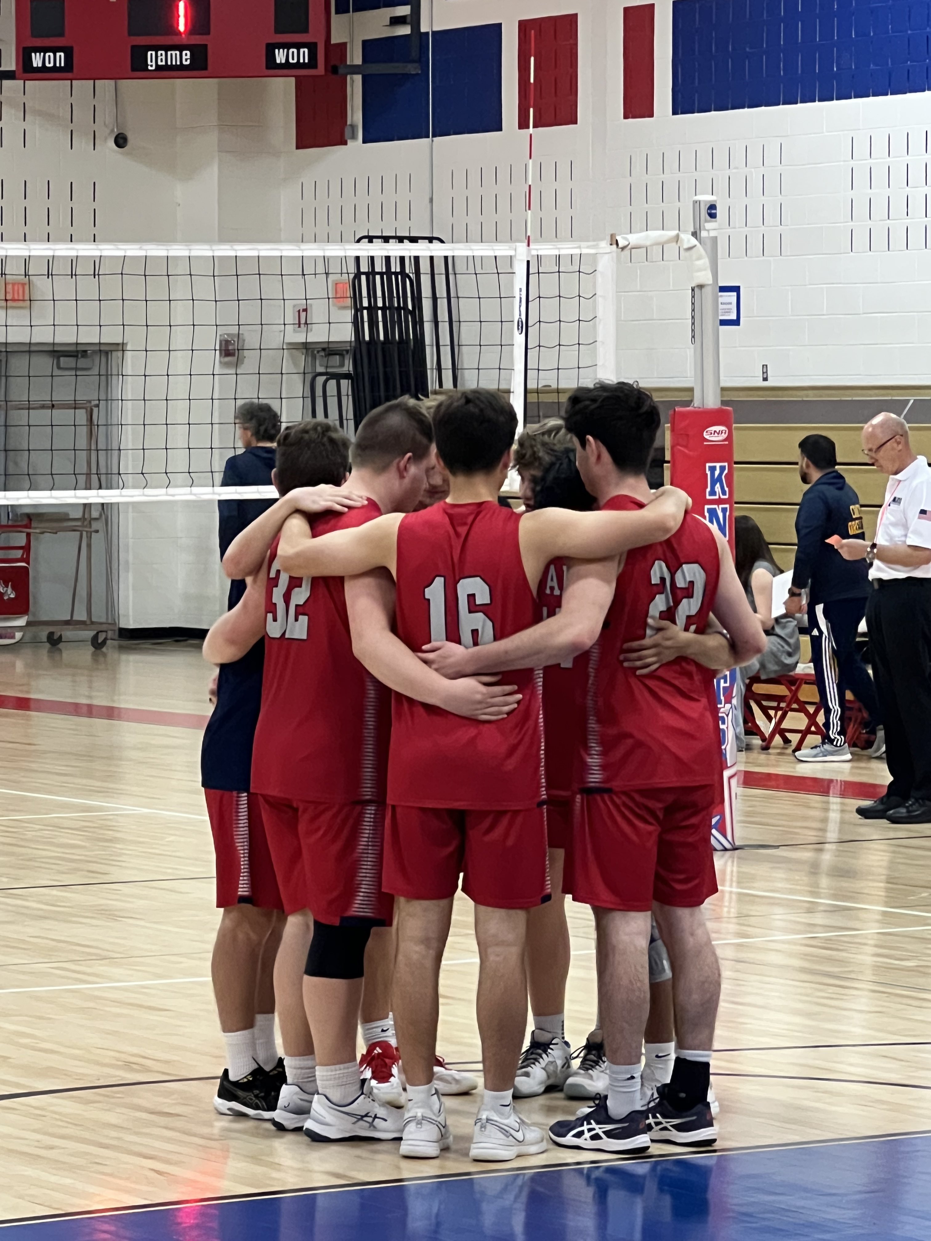 Volleyball players in a huddle. Red jerseys.