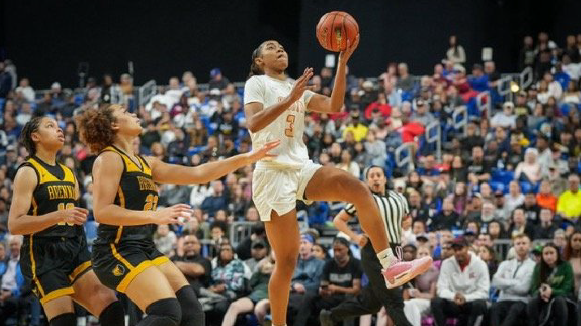A basketball player in a white jersey leaps high to make a shot, surrounded by a crowd of spectators in the background.