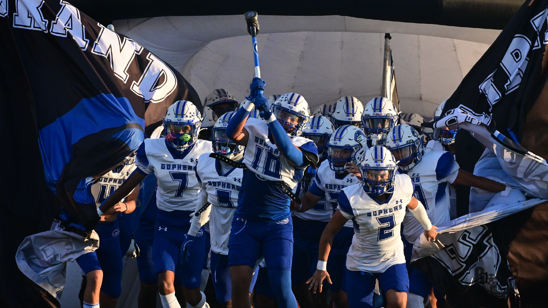 A group of football players in uniform, with helmets and jerseys, standing together and preparing to take the field.