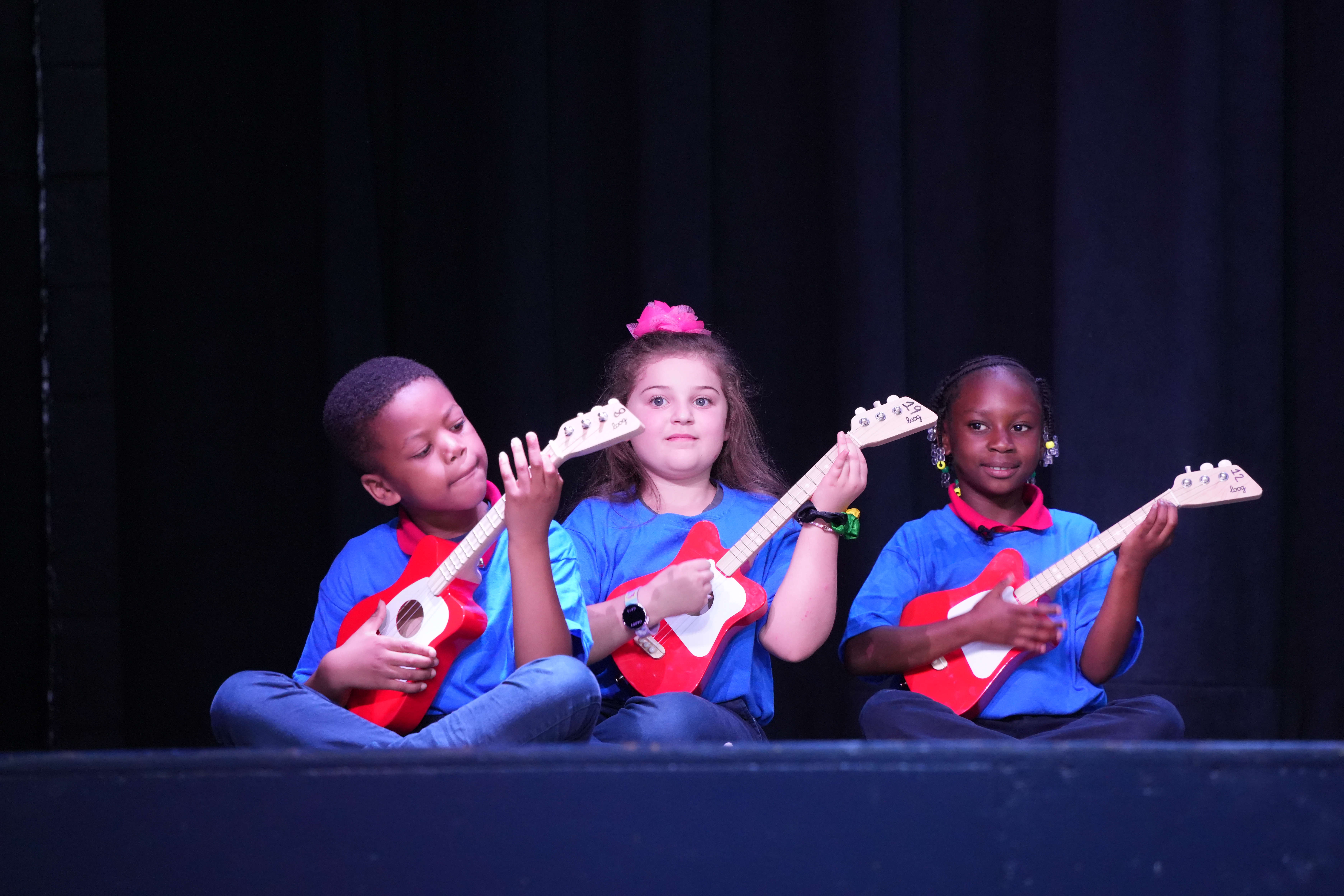three students playing guitars