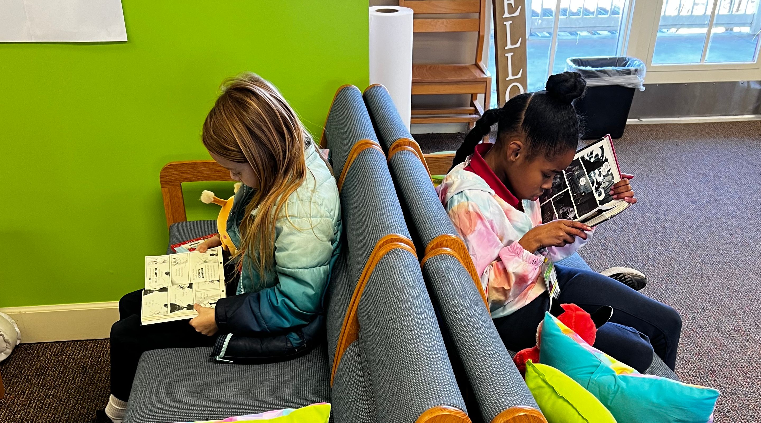 Two third graders enjoy reading on the library couches. 