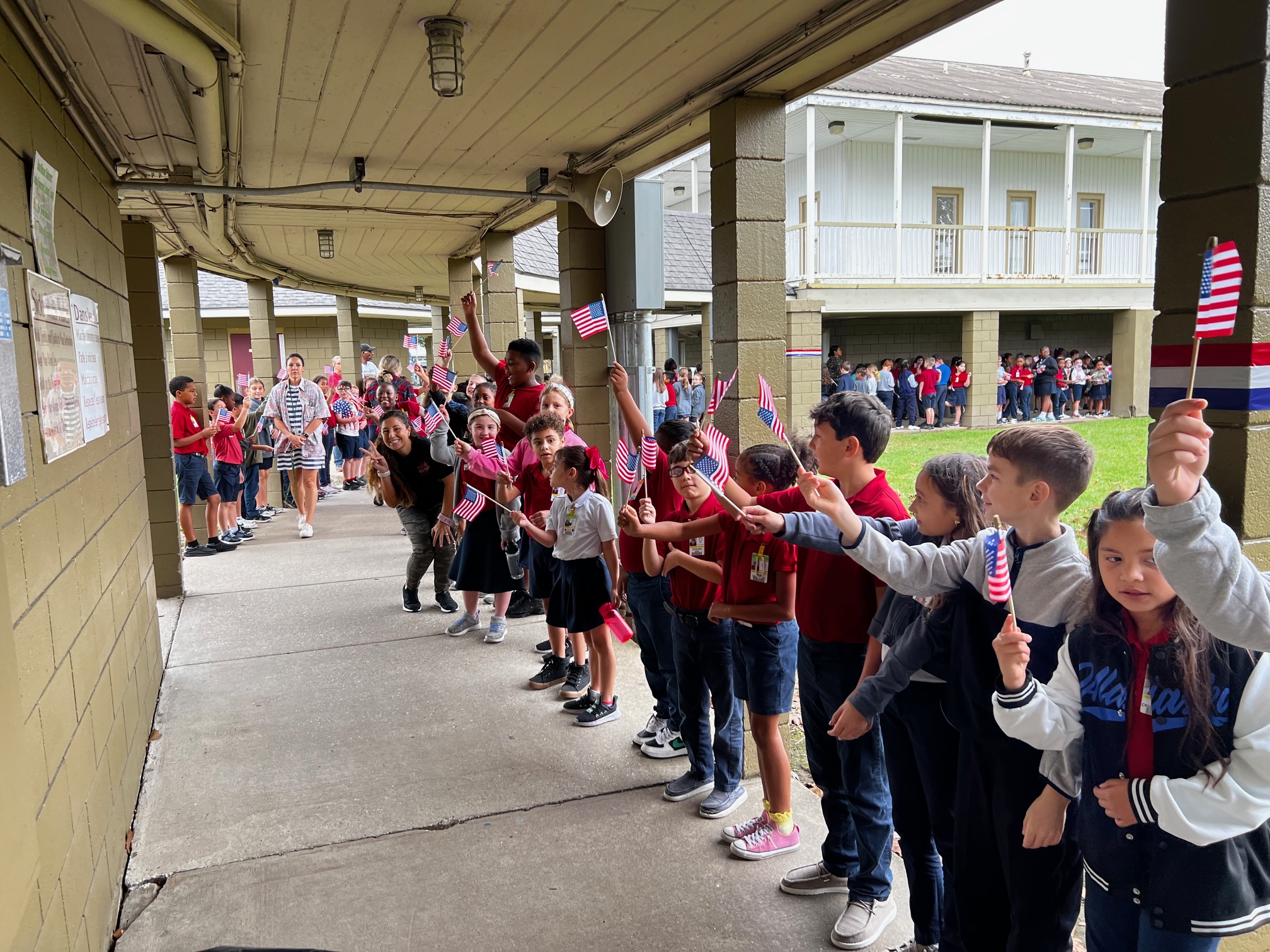 Students wave U.S. flags for the Veteran's walk during Teche's Veterans day celebration. 