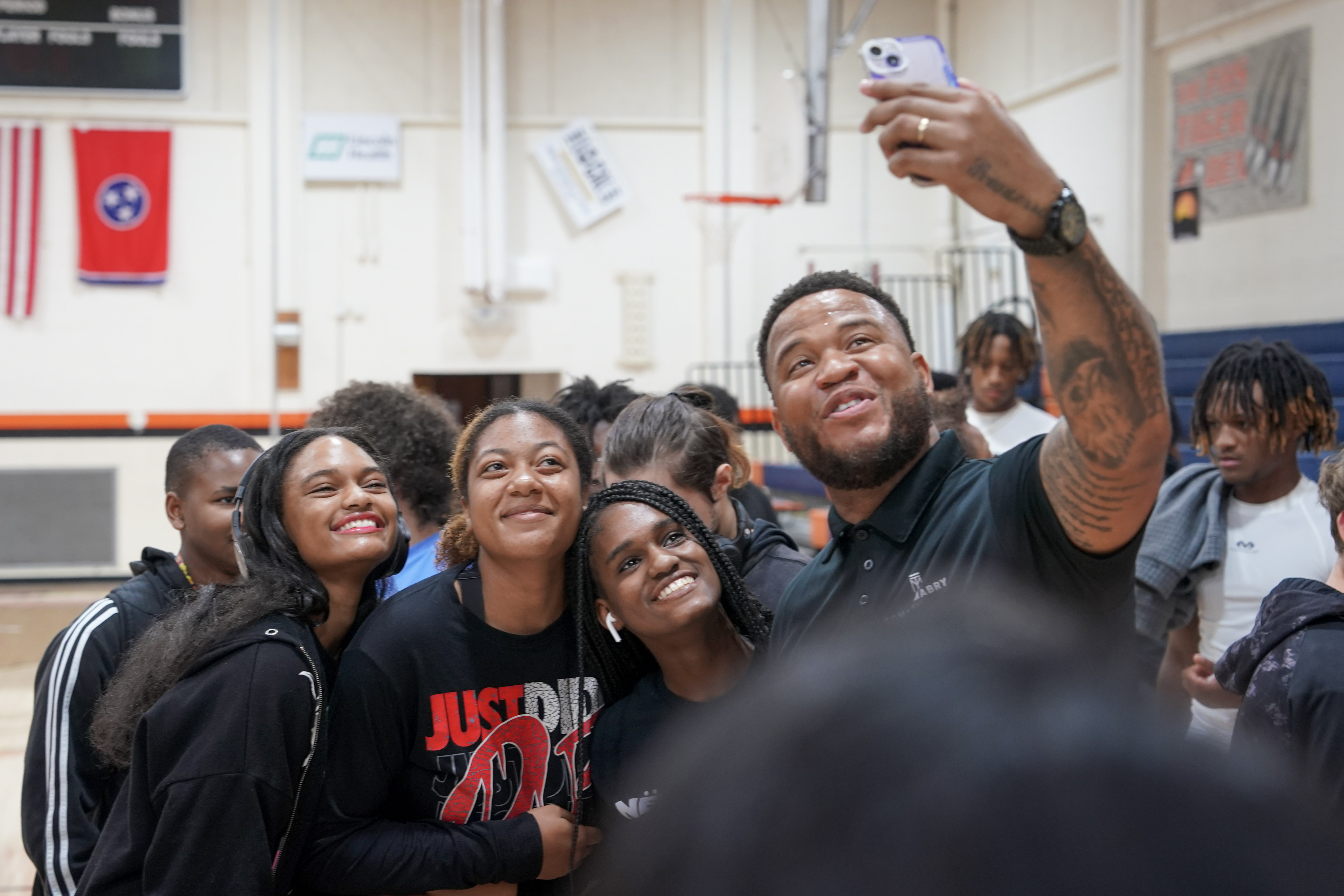 Man in black shirt and pants takes selfie with group of high school students