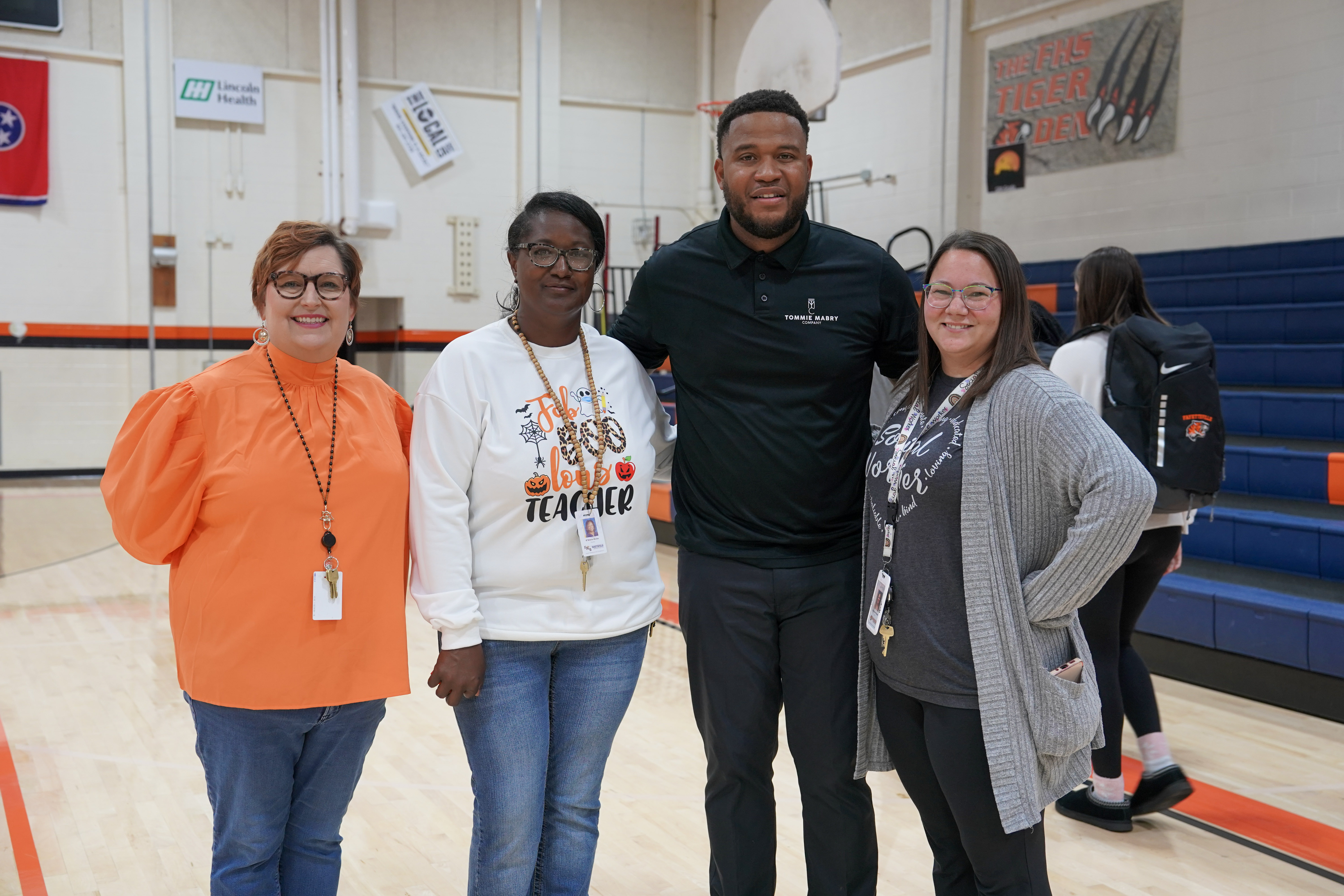 Man in black shirt and pants with three ladies inside gymnasium