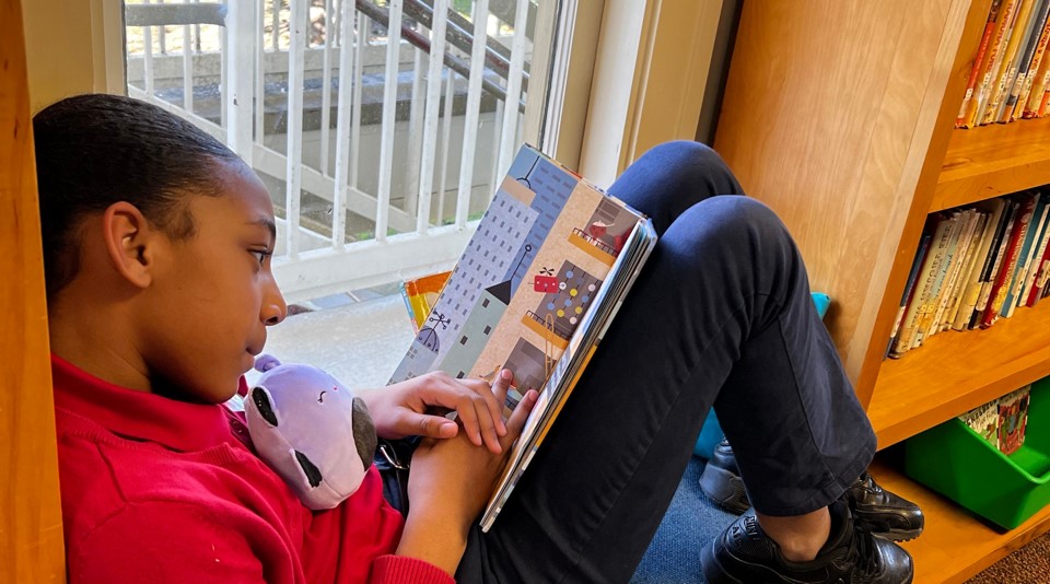 female student sitting in window sill reading