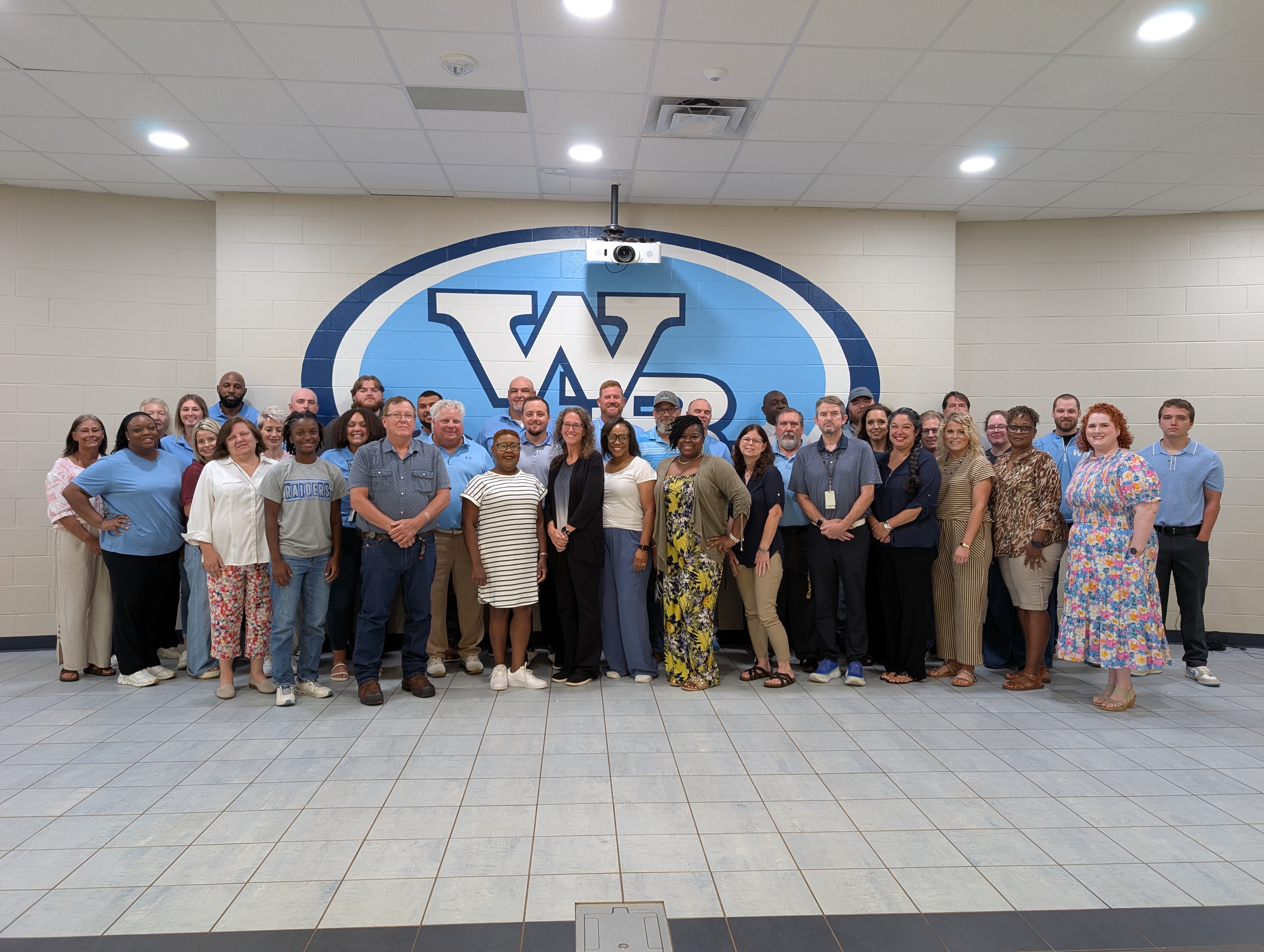 West Rusk High School teachers standing in front of the West Rusk logo