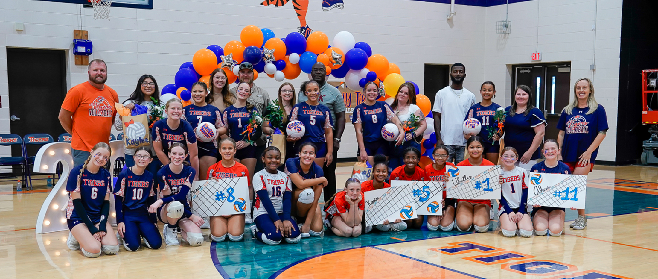 volleyball players pause for a photo with coaches and parents of 8th grade players