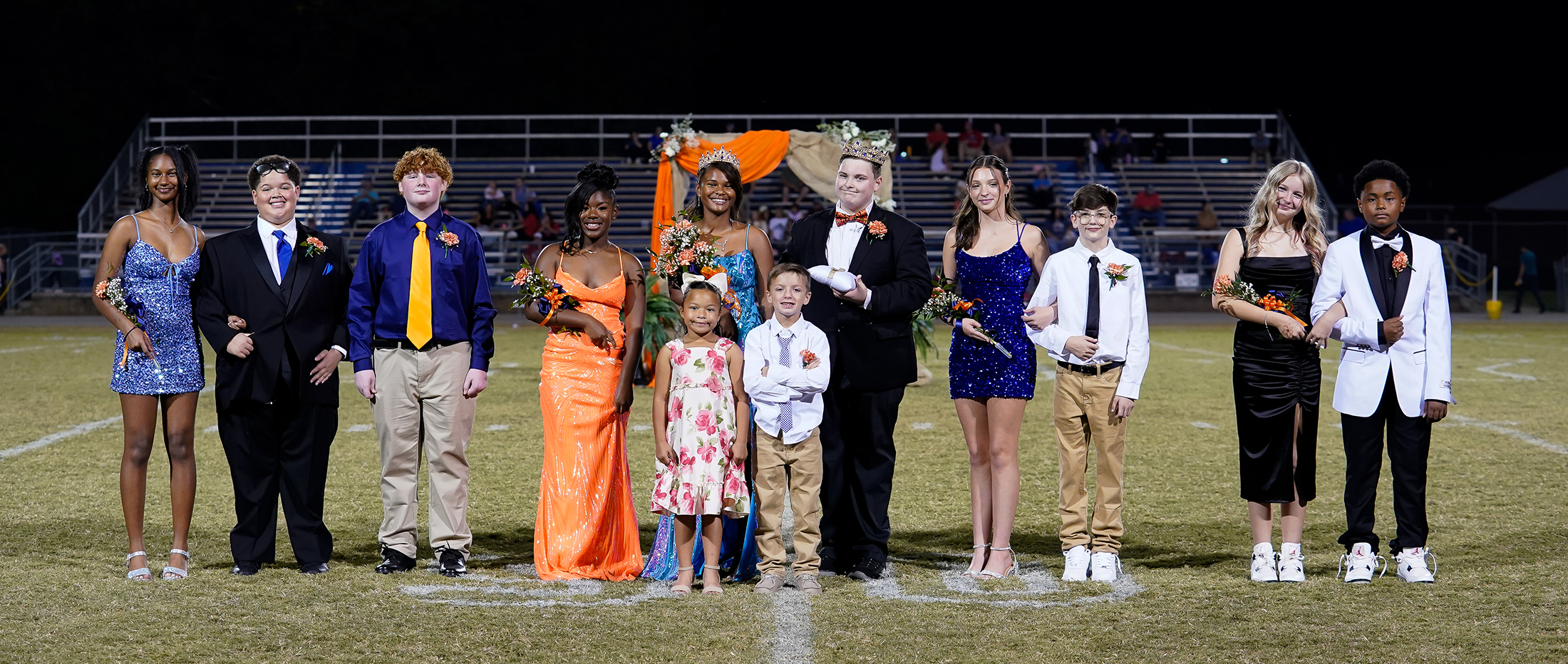 middle school students in homecoming court pause for photo on football field