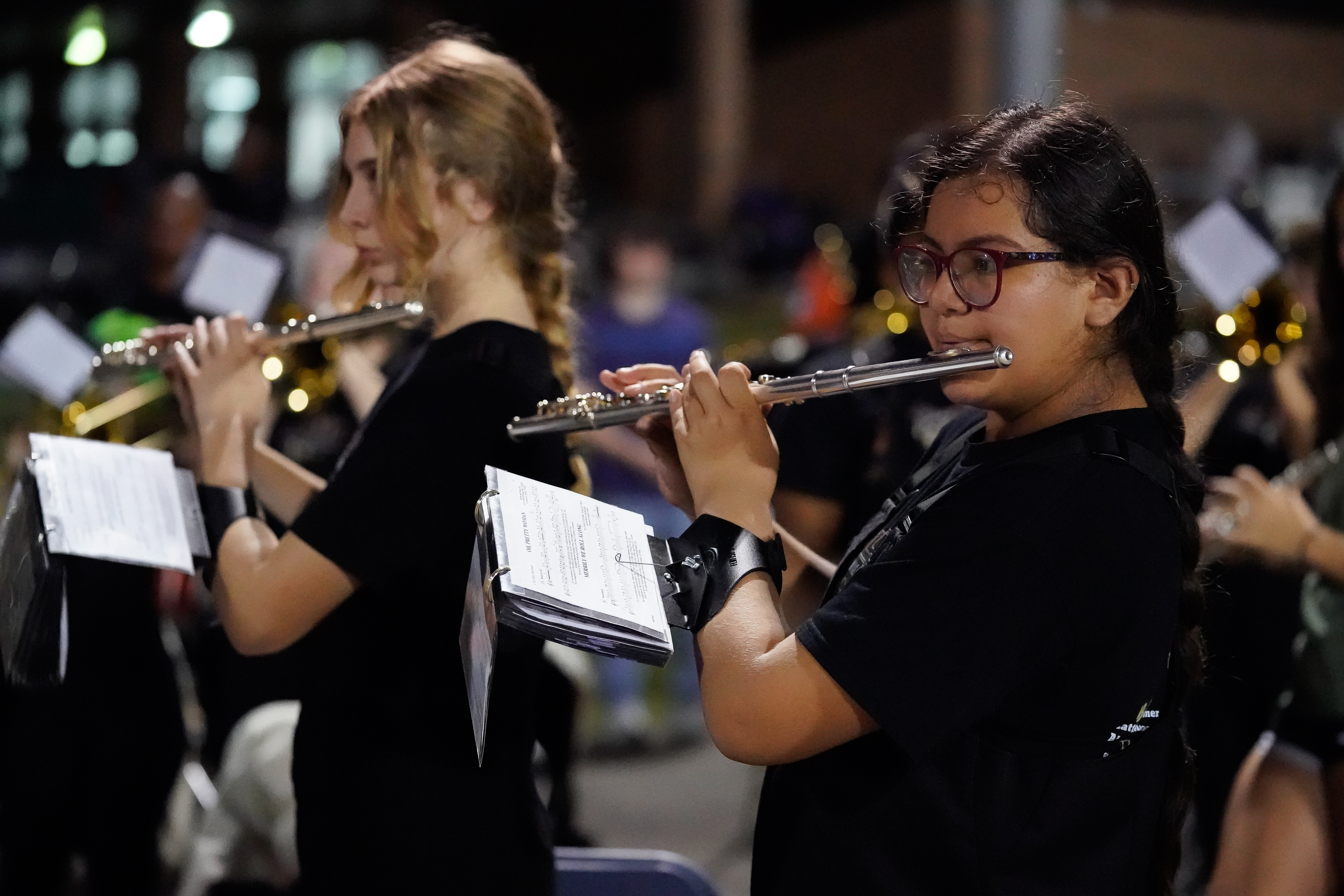 Tiger marching band flute players perform in the stands, focused on their music during the game.