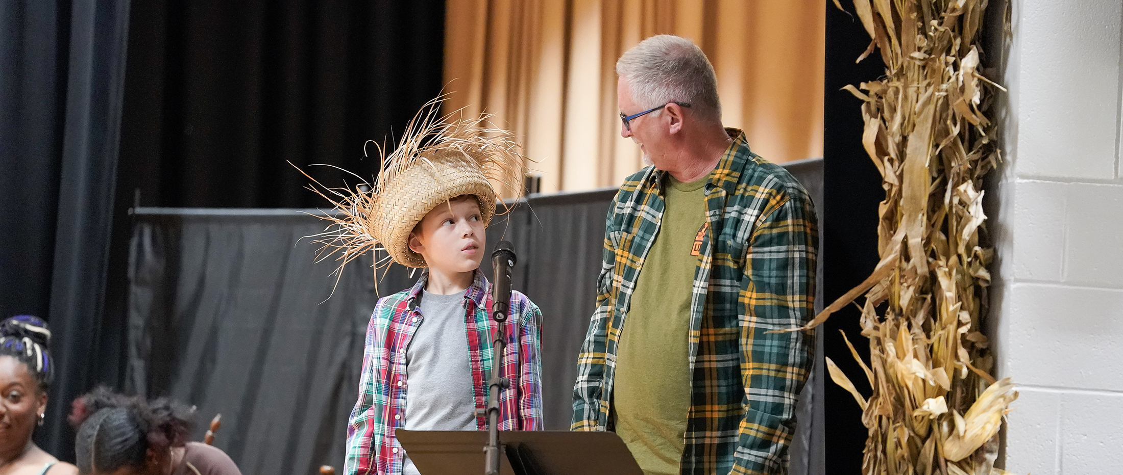 an adult and boy standing on stage in Hee Haw costumes