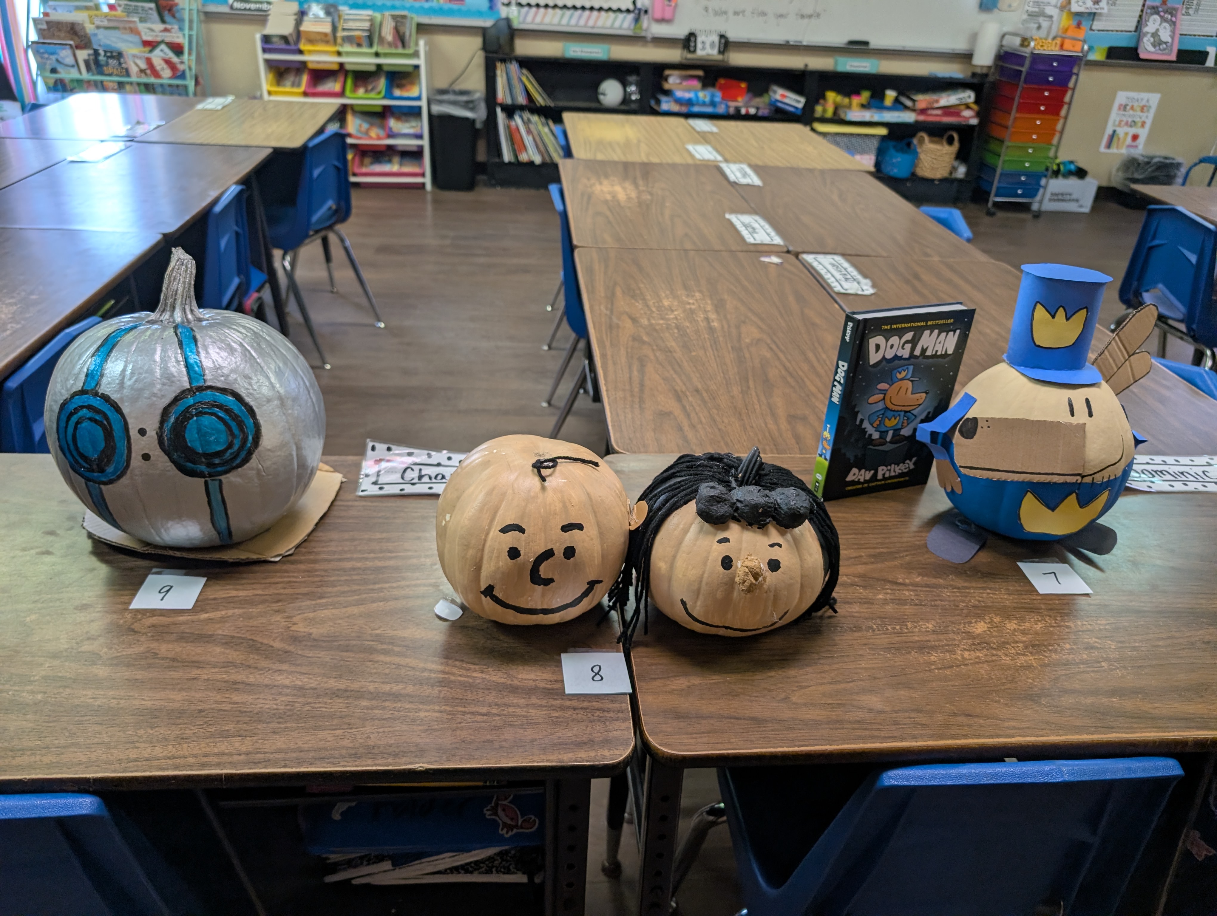 The image shows a classroom setting with various educational materials and decorations, including pumpkins painted to resemble characters from a popular media franchise.