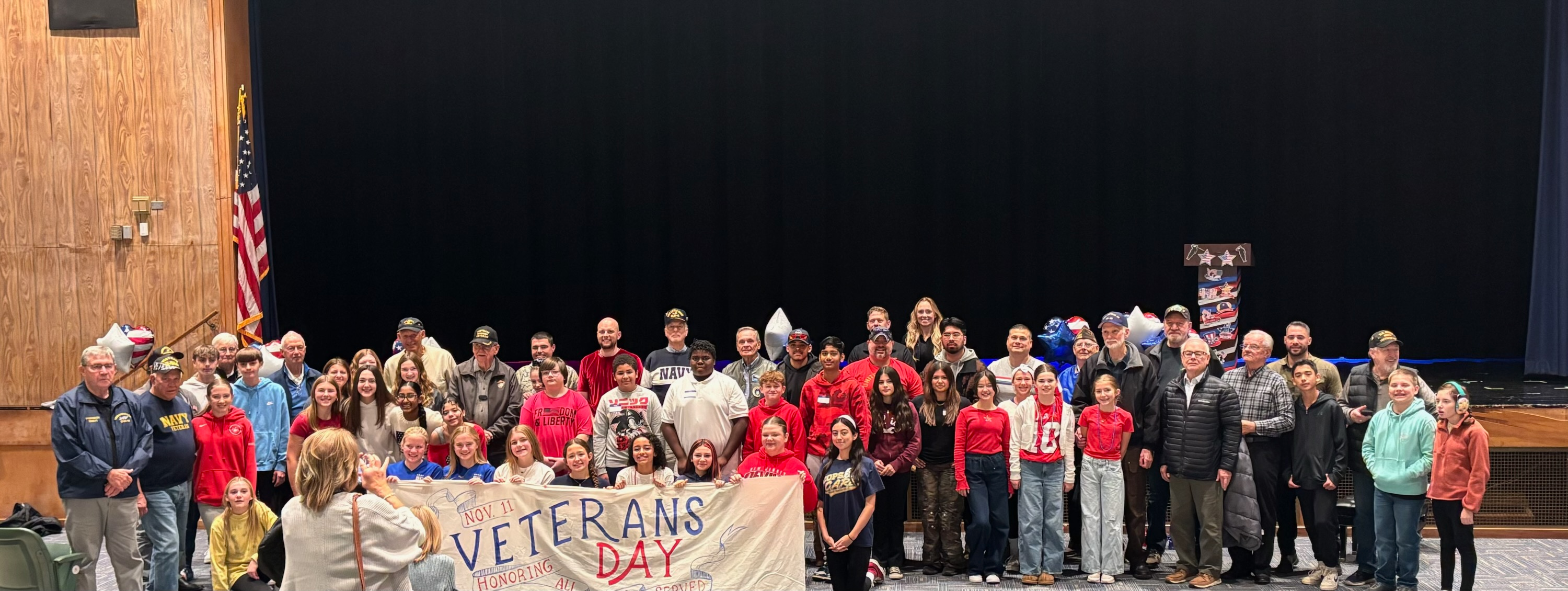 Students stand with veterans on stage.