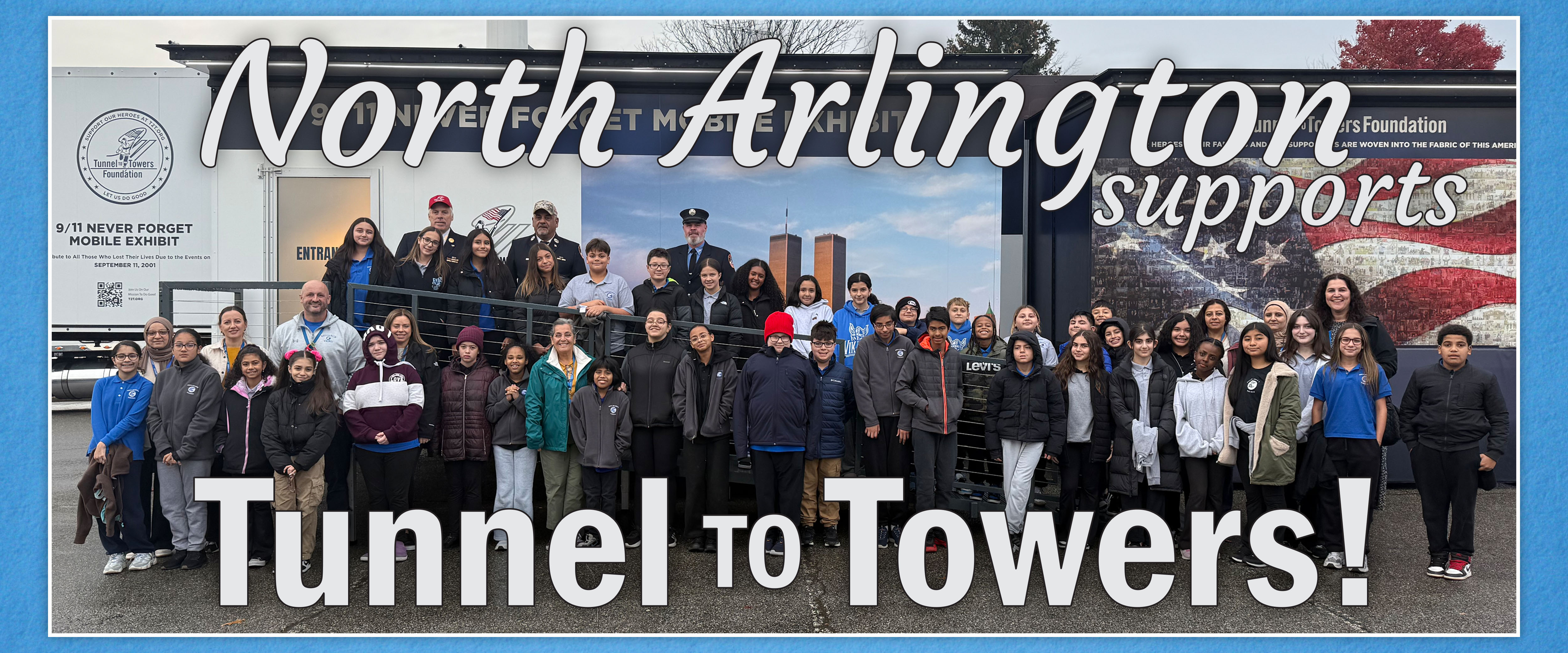 A group of people stand in front of a trailer with "North Arlington supports Tunnel to Towers!" written on it, and a mural of the Twin Towers and an American flag in the background.