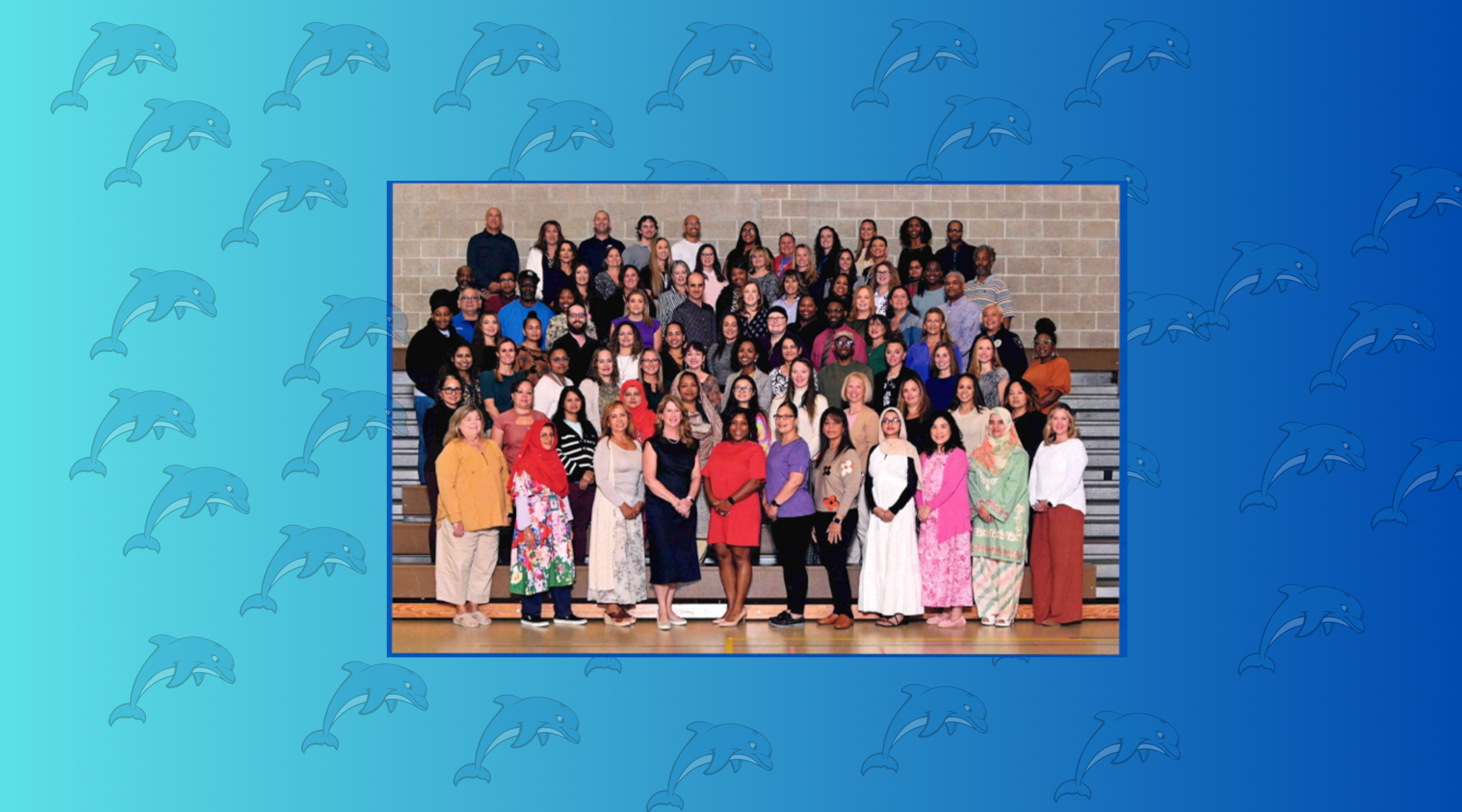 A large group of people, mostly women, are standing together in a formal group photo setting, with a background of blue and silhouetted dolphins.