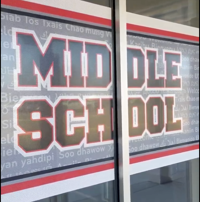Large red and gray letters spelling "MIDDLE SCHOOL" are superimposed on a background of various languages, with a red and white striped border framing the text.