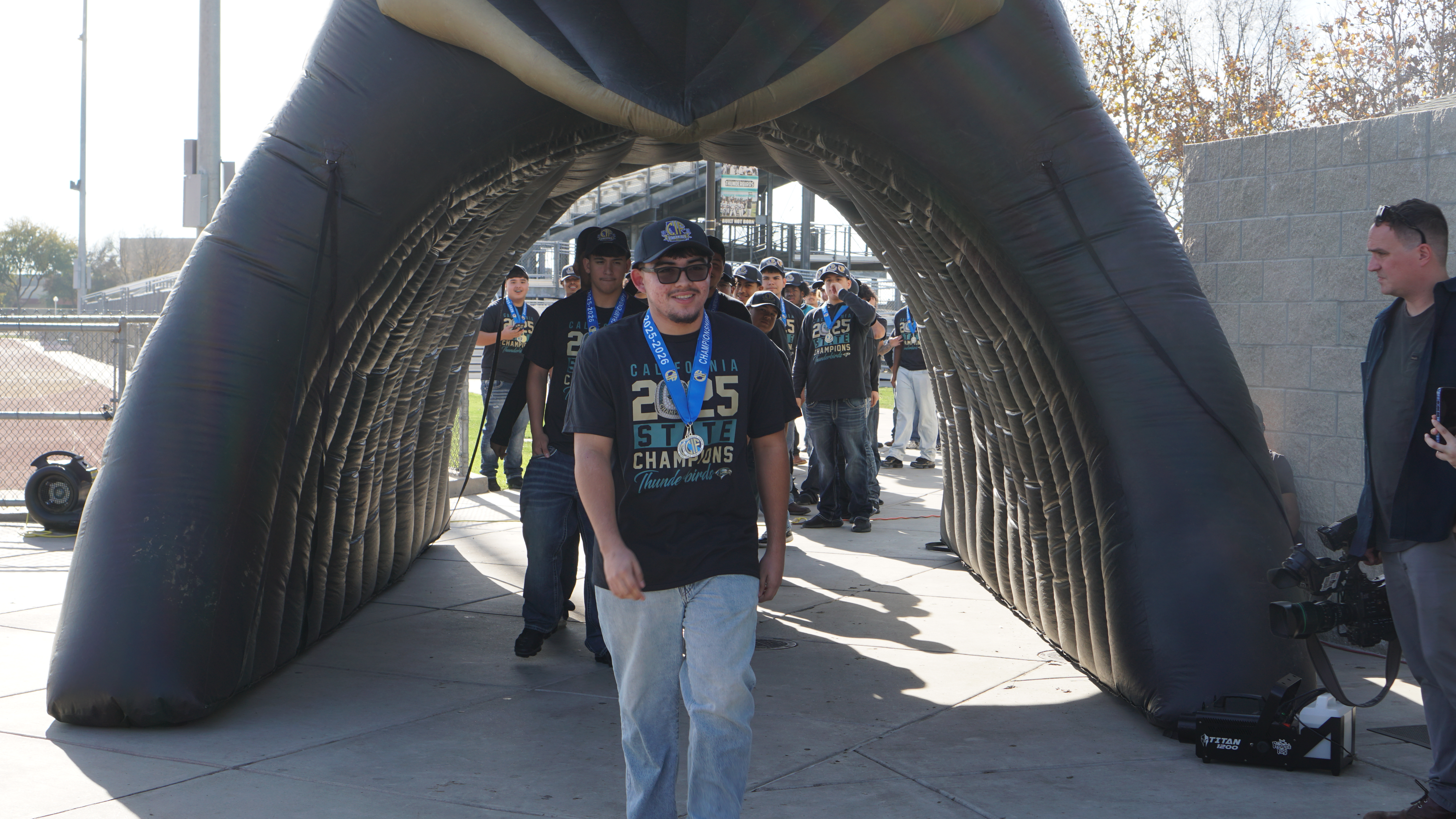 The image shows a large, arched structure with people walking through it, creating a sense of movement and activity in the background.