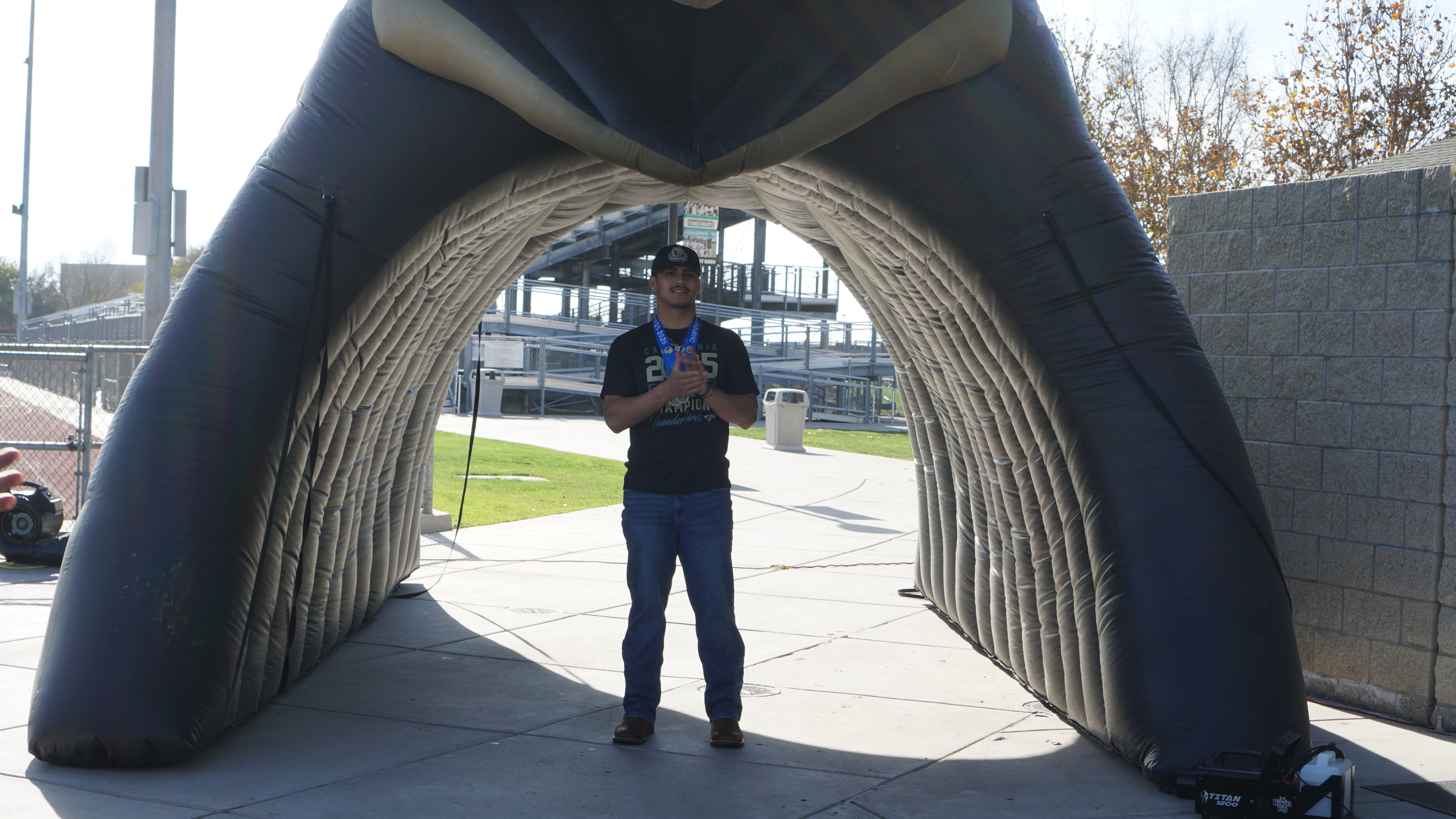 A person standing in an arched walkway, with a cityscape visible in the background.