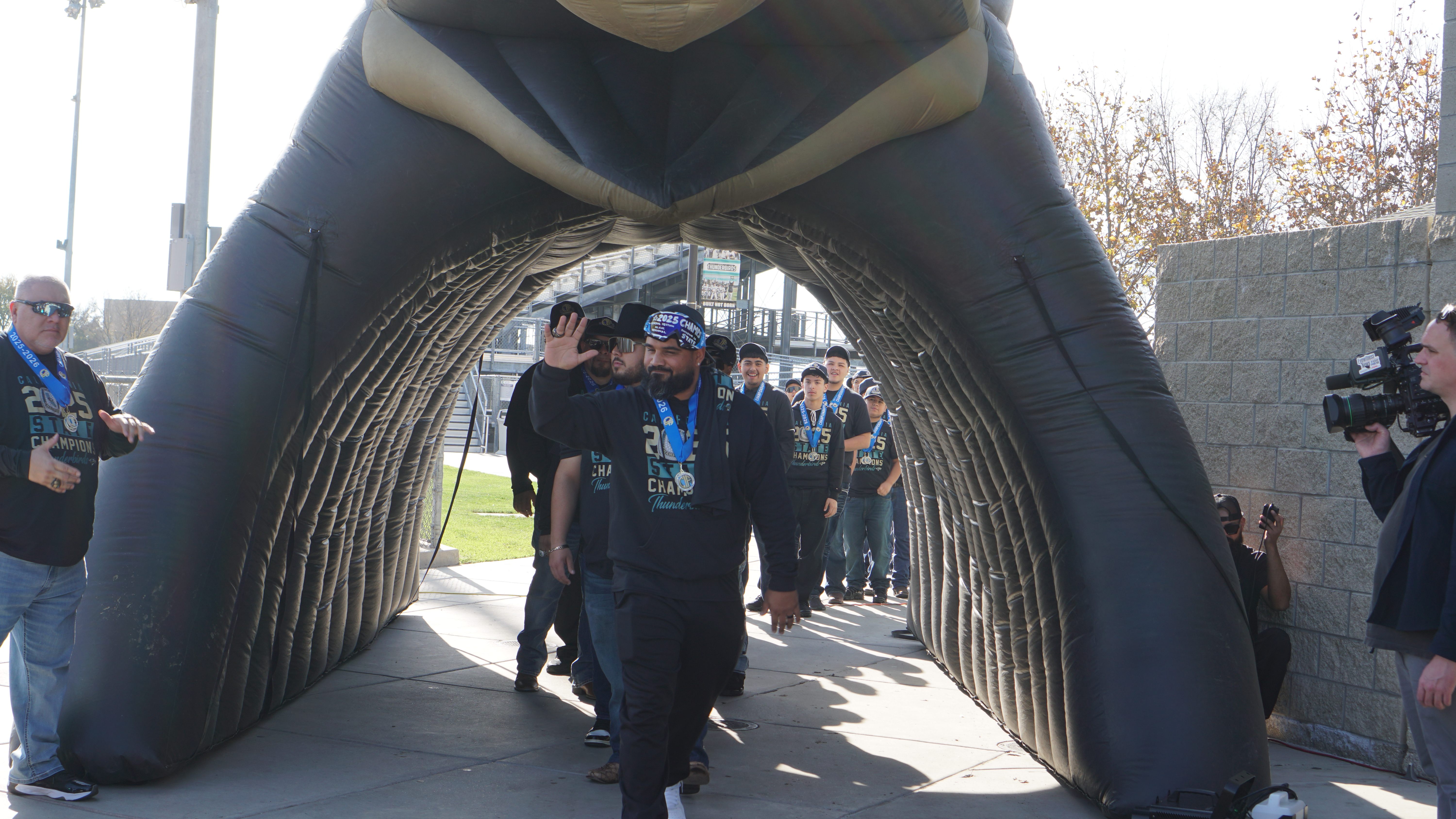 A large, arched structure made of metal and wood frames a group of people standing in the background, creating an intriguing and visually striking scene.