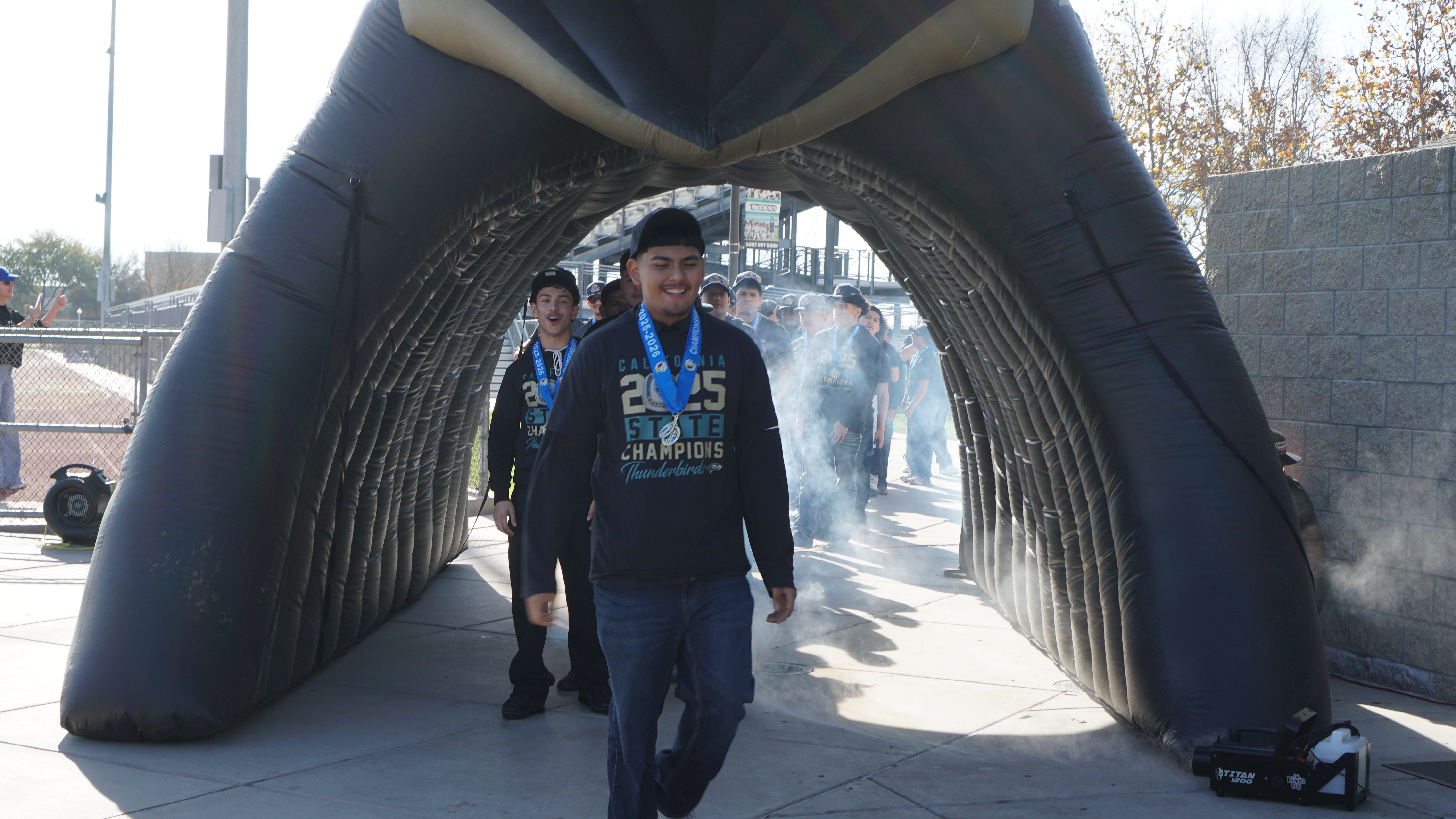 The image shows a person wearing a dark-colored outfit standing in an arched entryway, with a cityscape visible in the background.