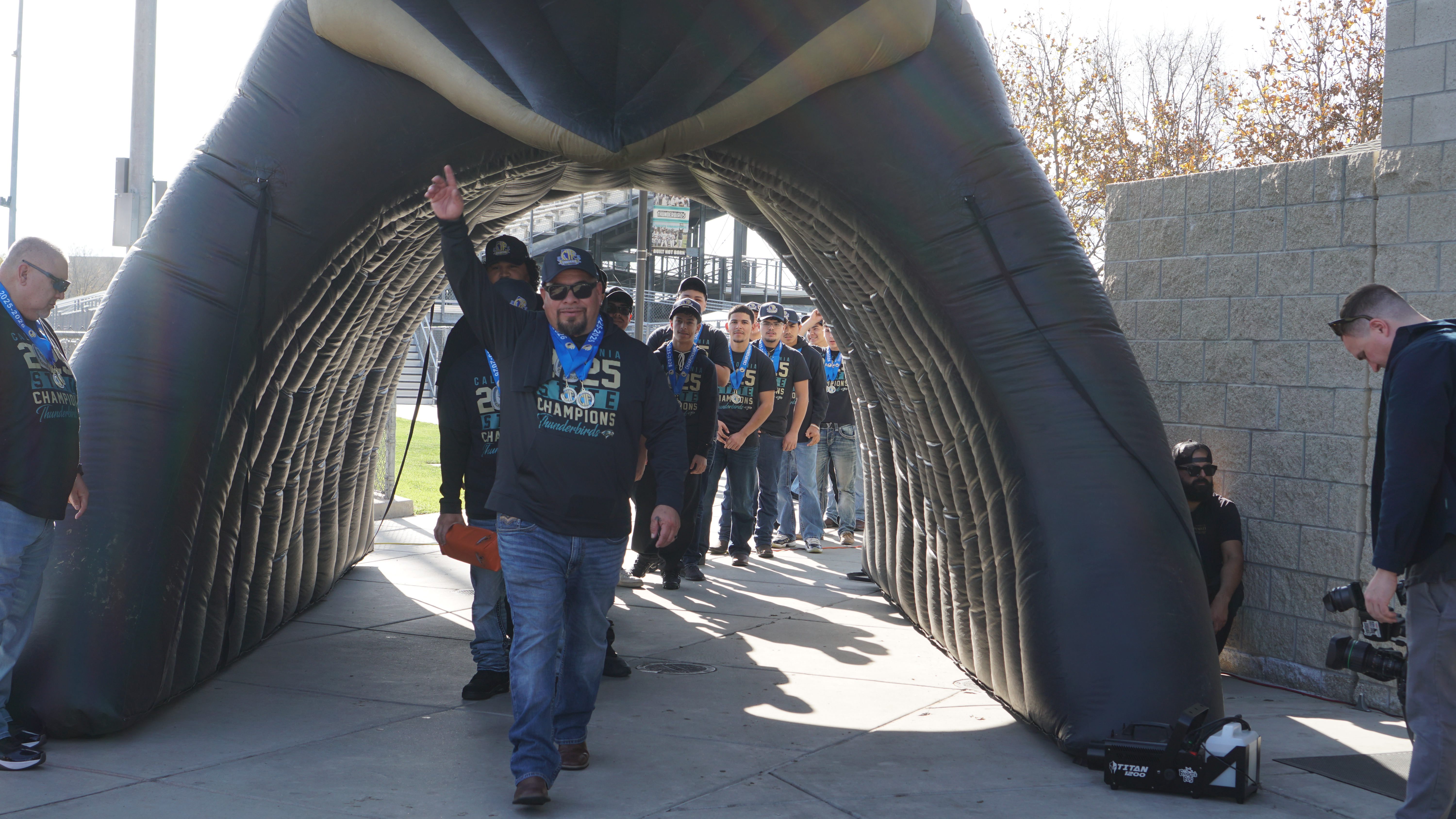 A group of people walking through an arched entryway, with a large inflatable structure in the background.