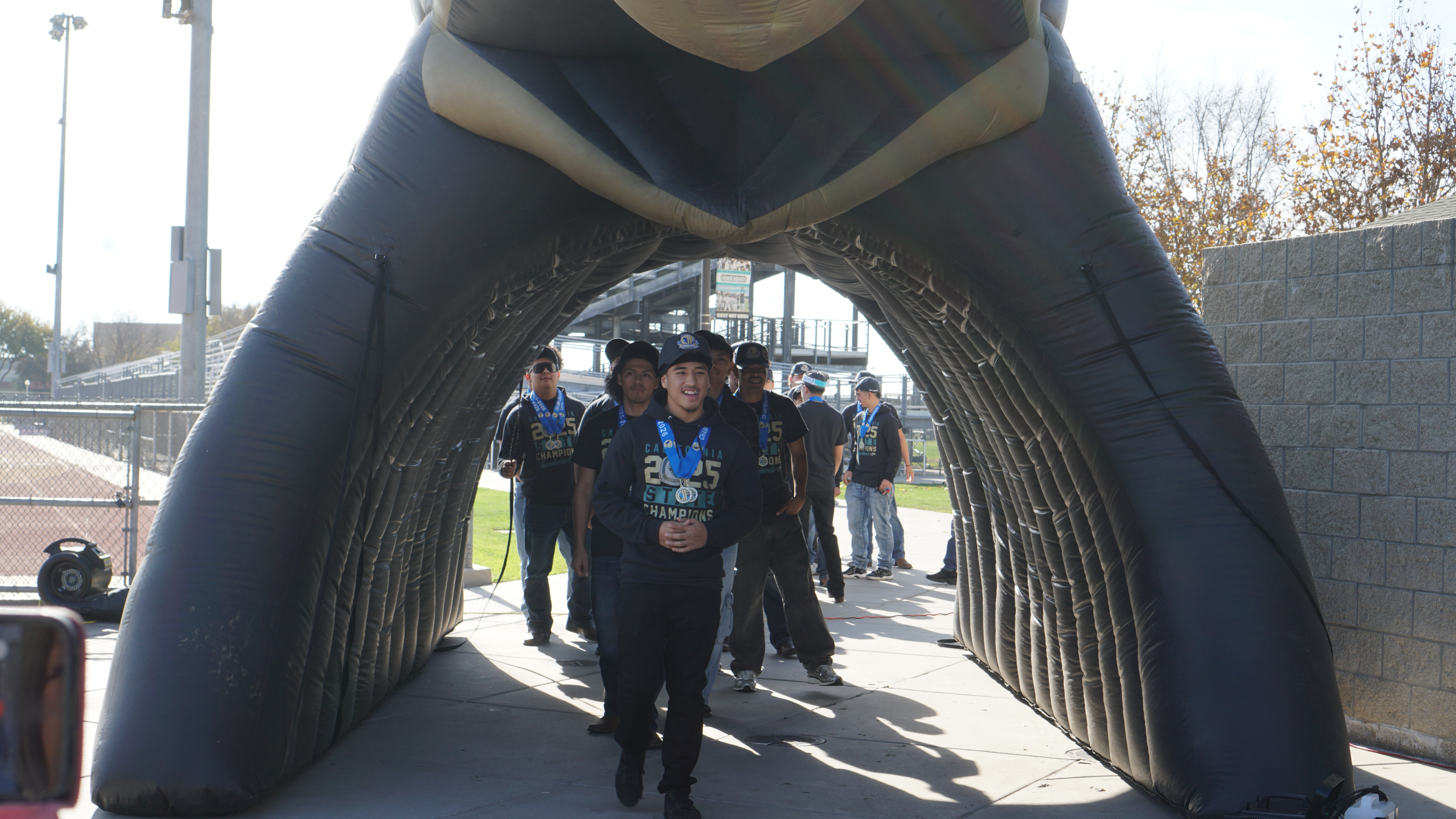 A group of people walking through an arched structure, with a cityscape visible in the background.