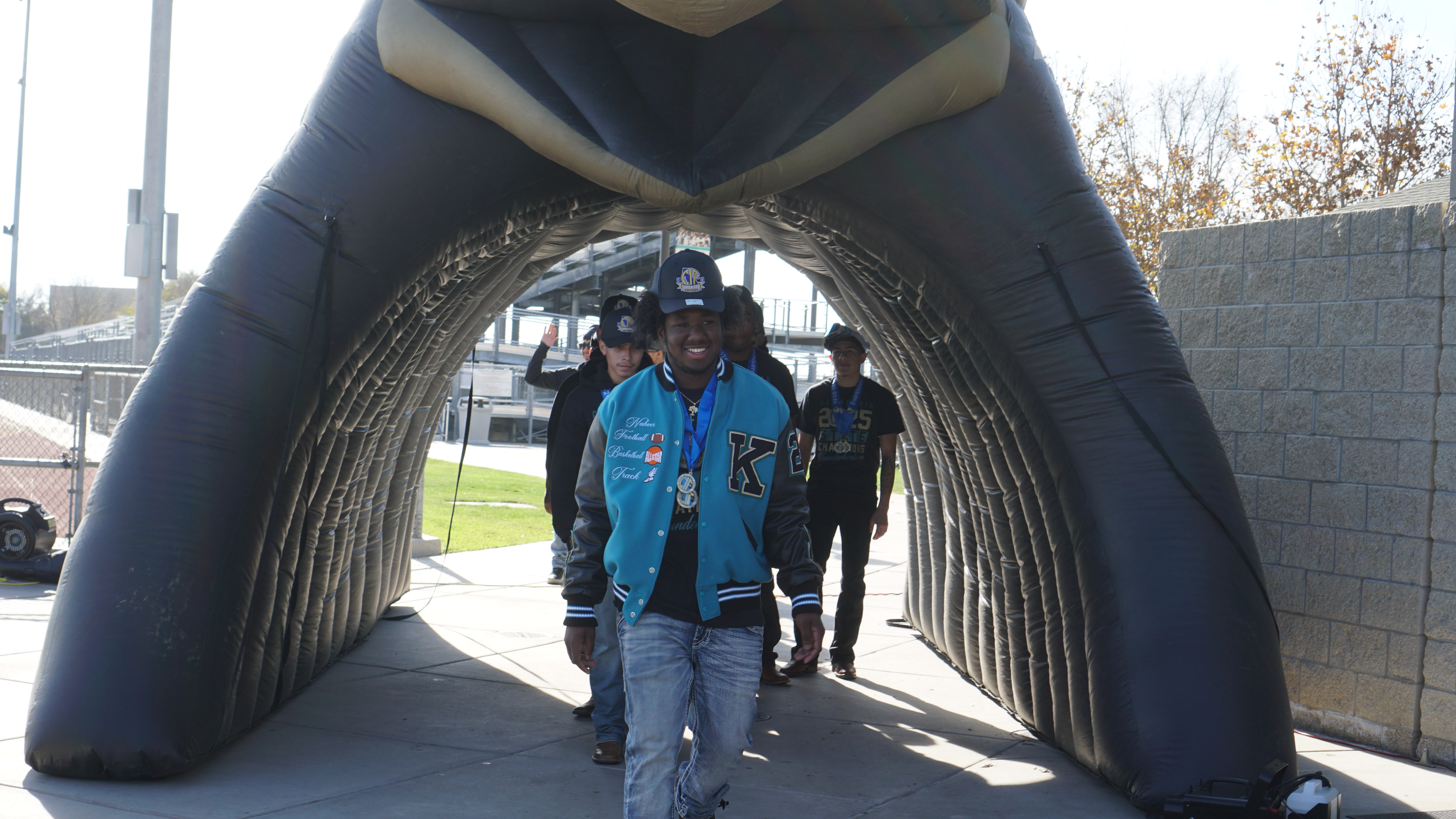 A group of people walking through an arched structure, with a cityscape visible in the background.