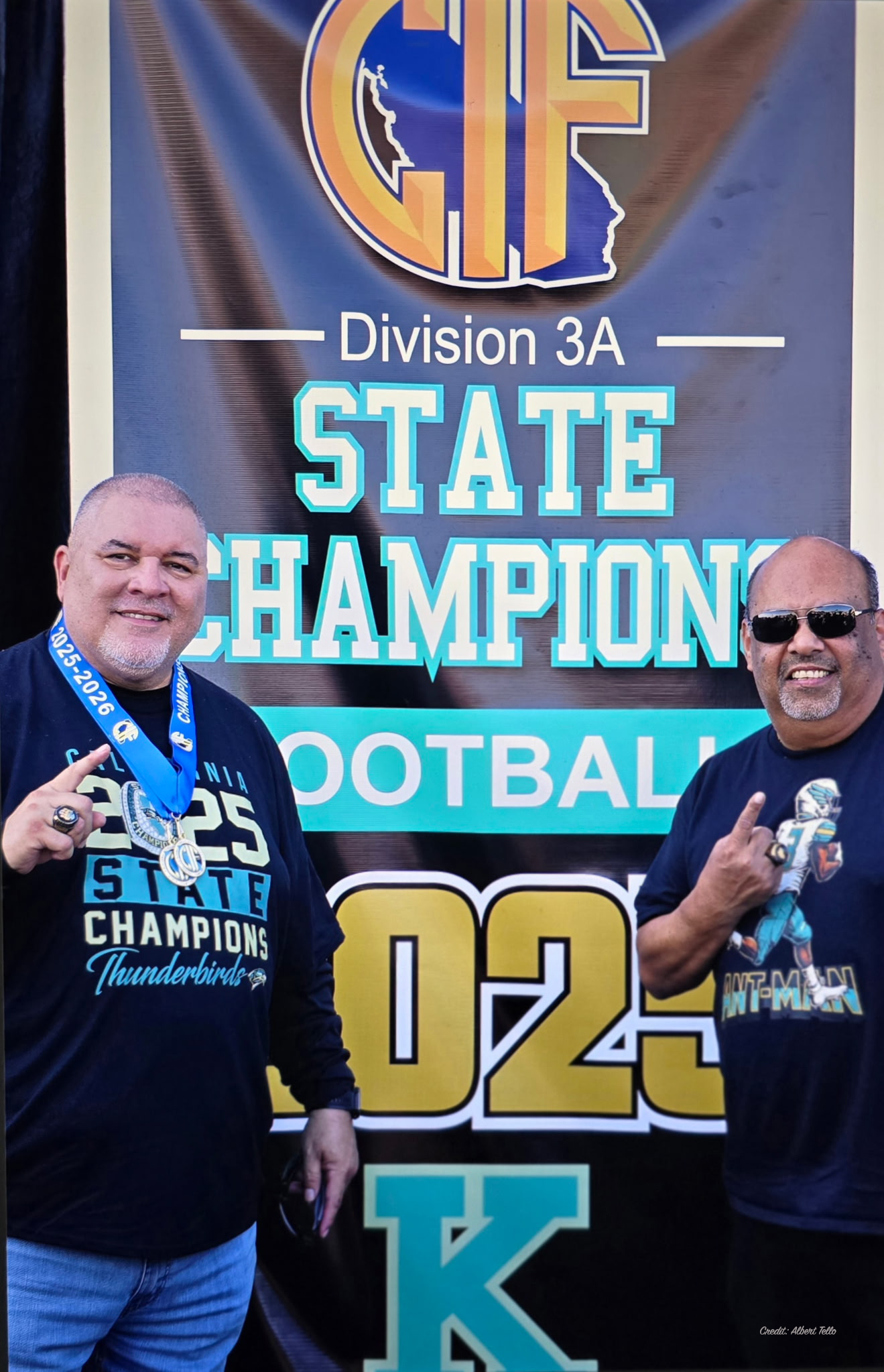 The image shows two men posing in front of a banner celebrating a Division 3A state championship in football.