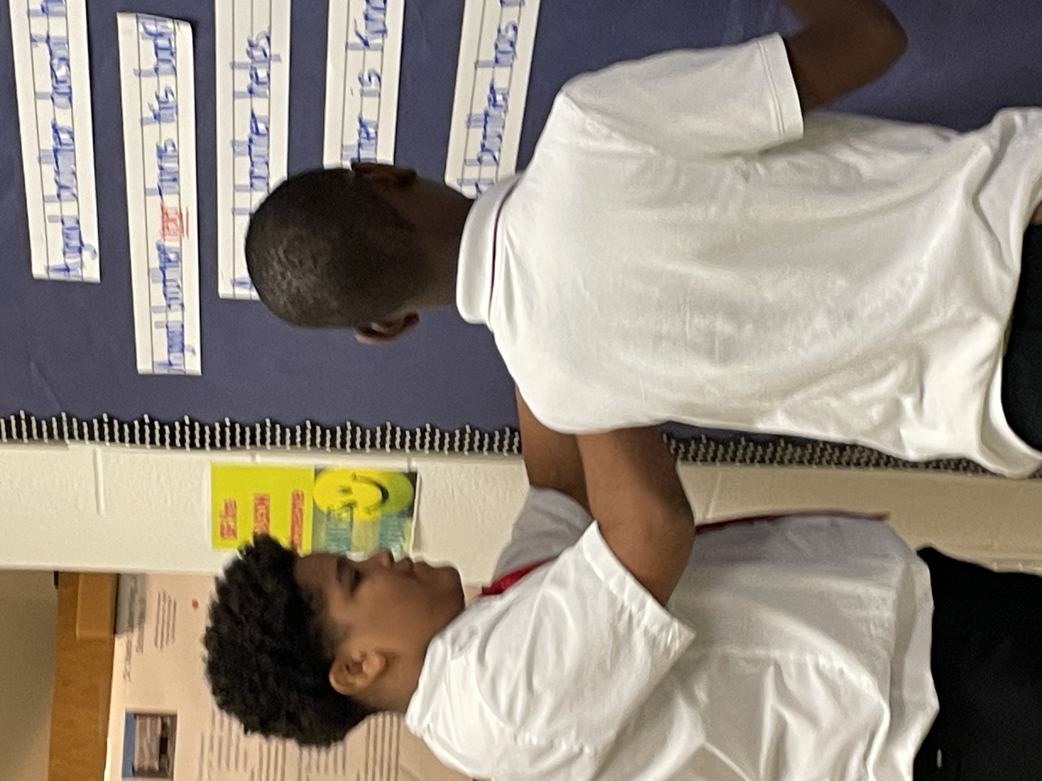 Two mlk boys academy students creating a bulletin board for brotherhood