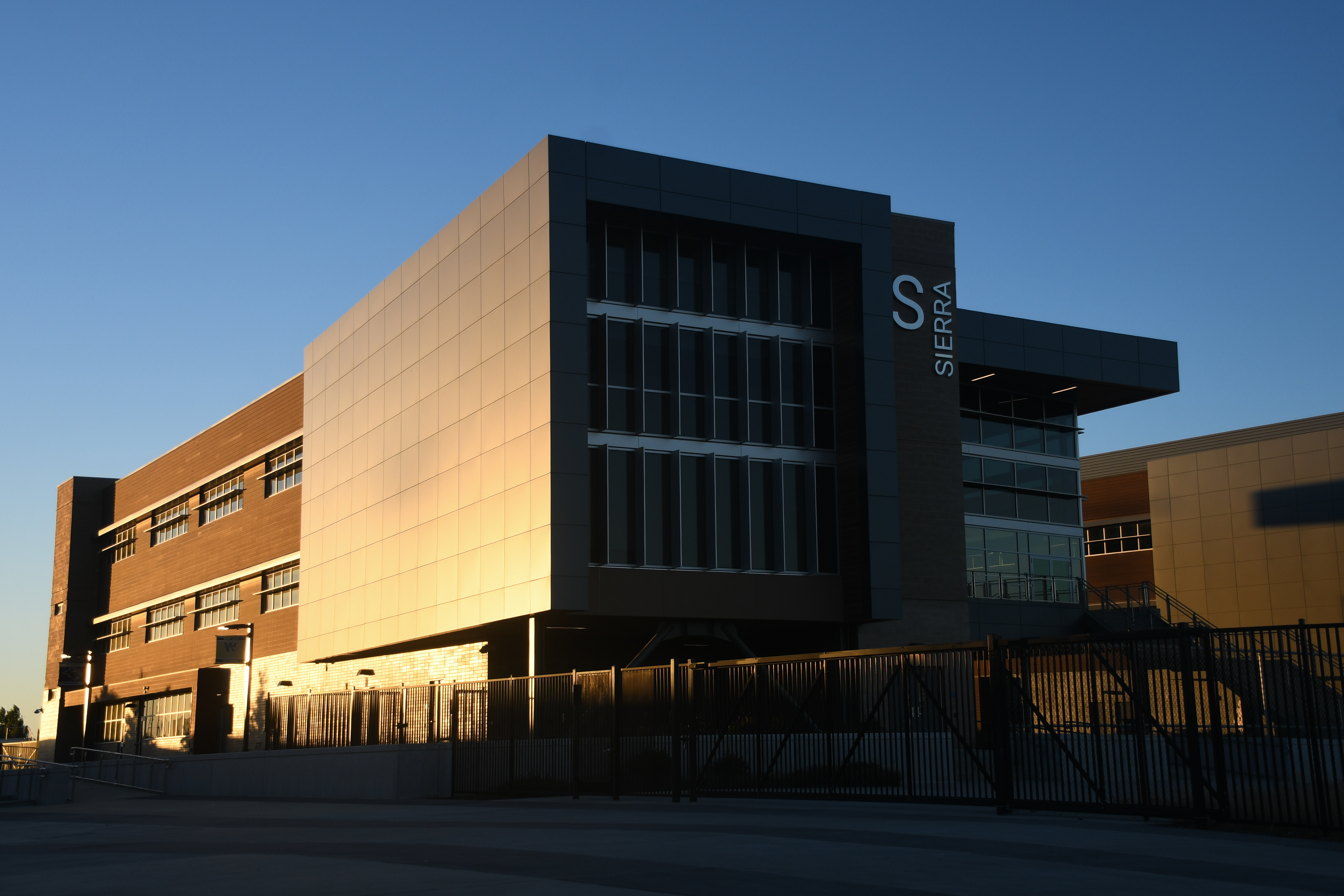 A modern, angular building with a prominent "Sensis" logo stands in the foreground, set against a clear blue sky in the background.