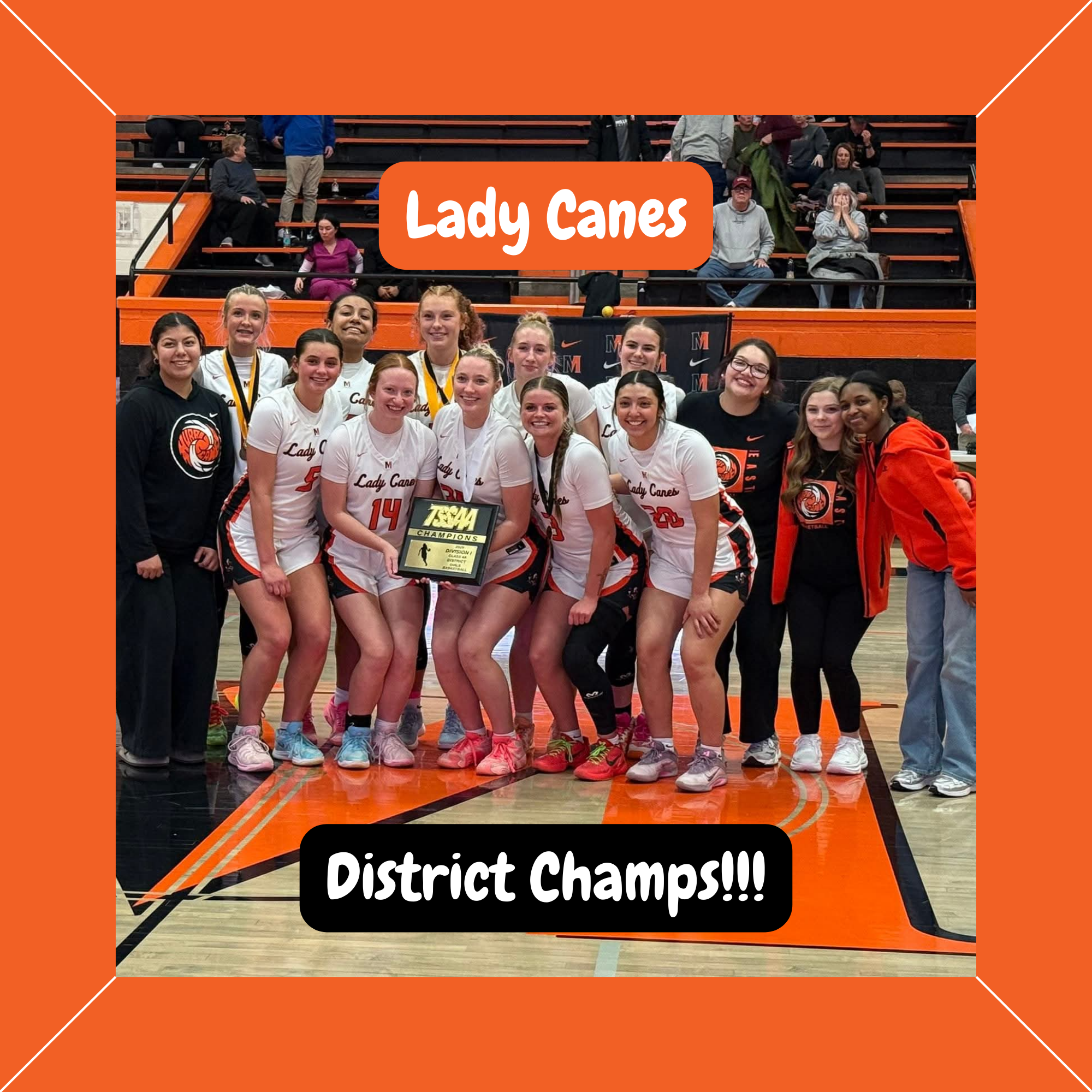A group photo of the Lady Canes girls' basketball team smiling and posing on the court while holding their TSSAA District Championship plaque.
