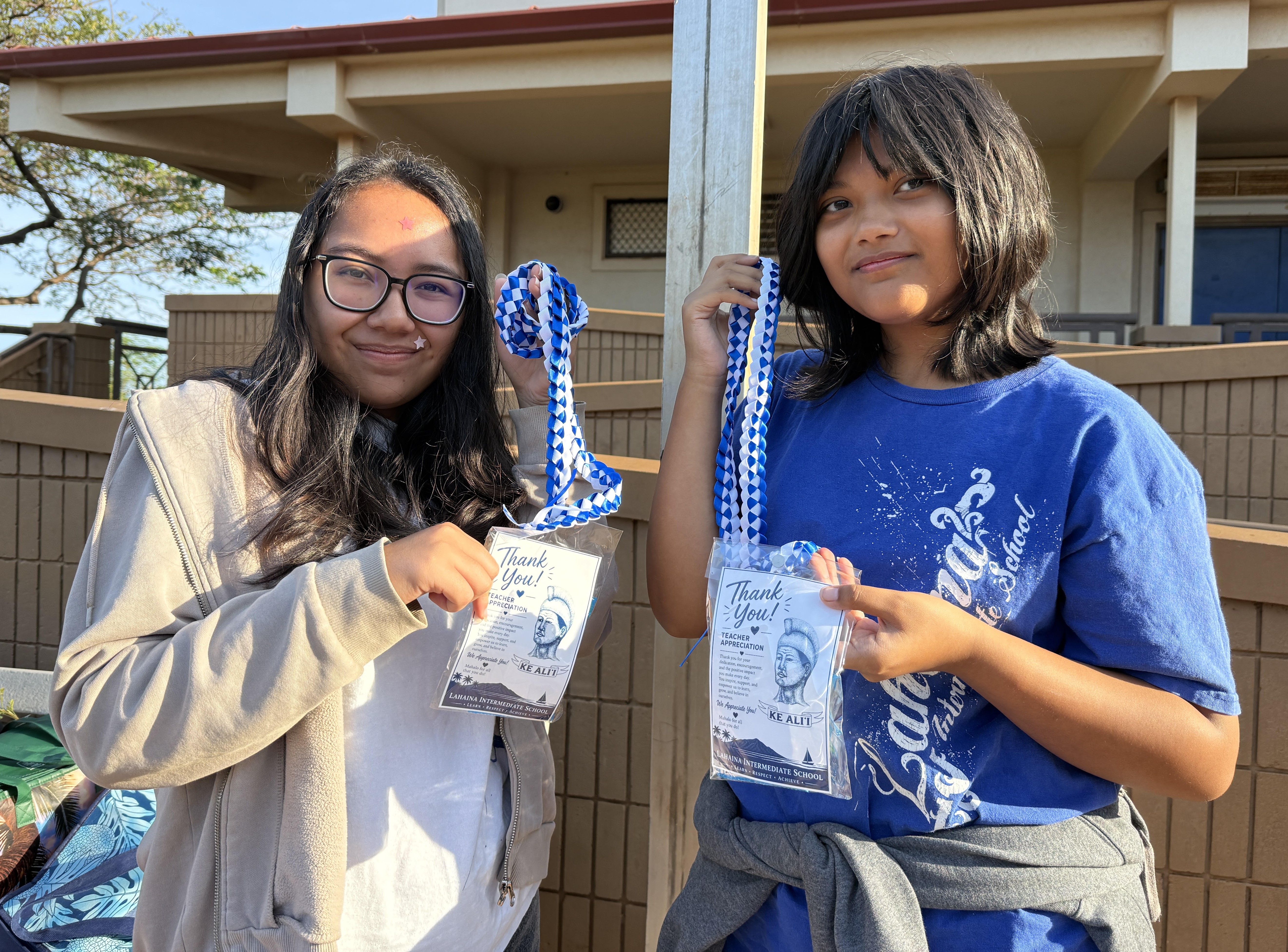 Two students displaying leis that they made.