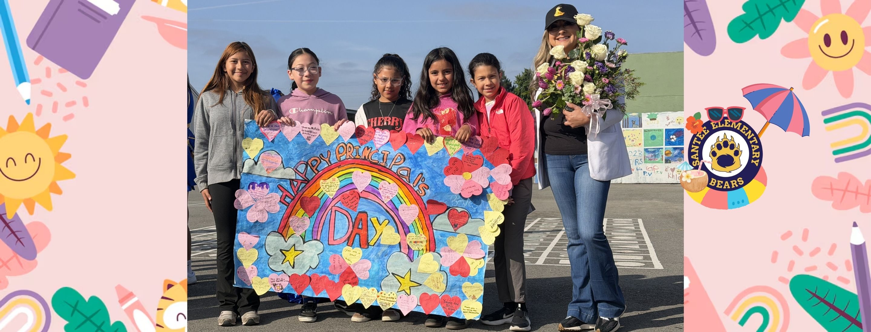 Five young girls stand in the foreground holding a colorful rainbow-themed poster, while a woman holding a bouquet of flowers stands to their right, with a school building and playground visible in the background.