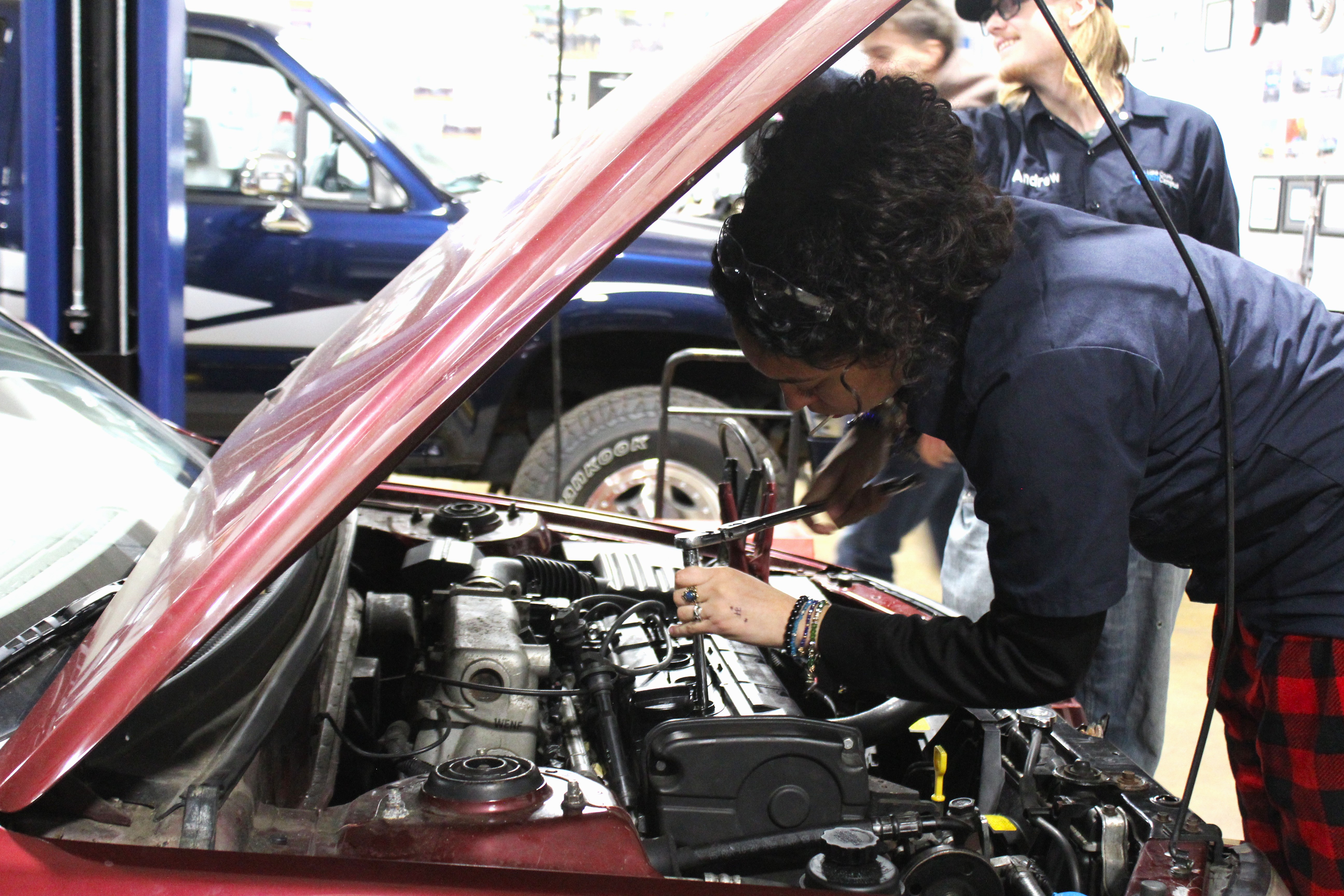 An automotive student is reading the oil levels on a car's dipstick