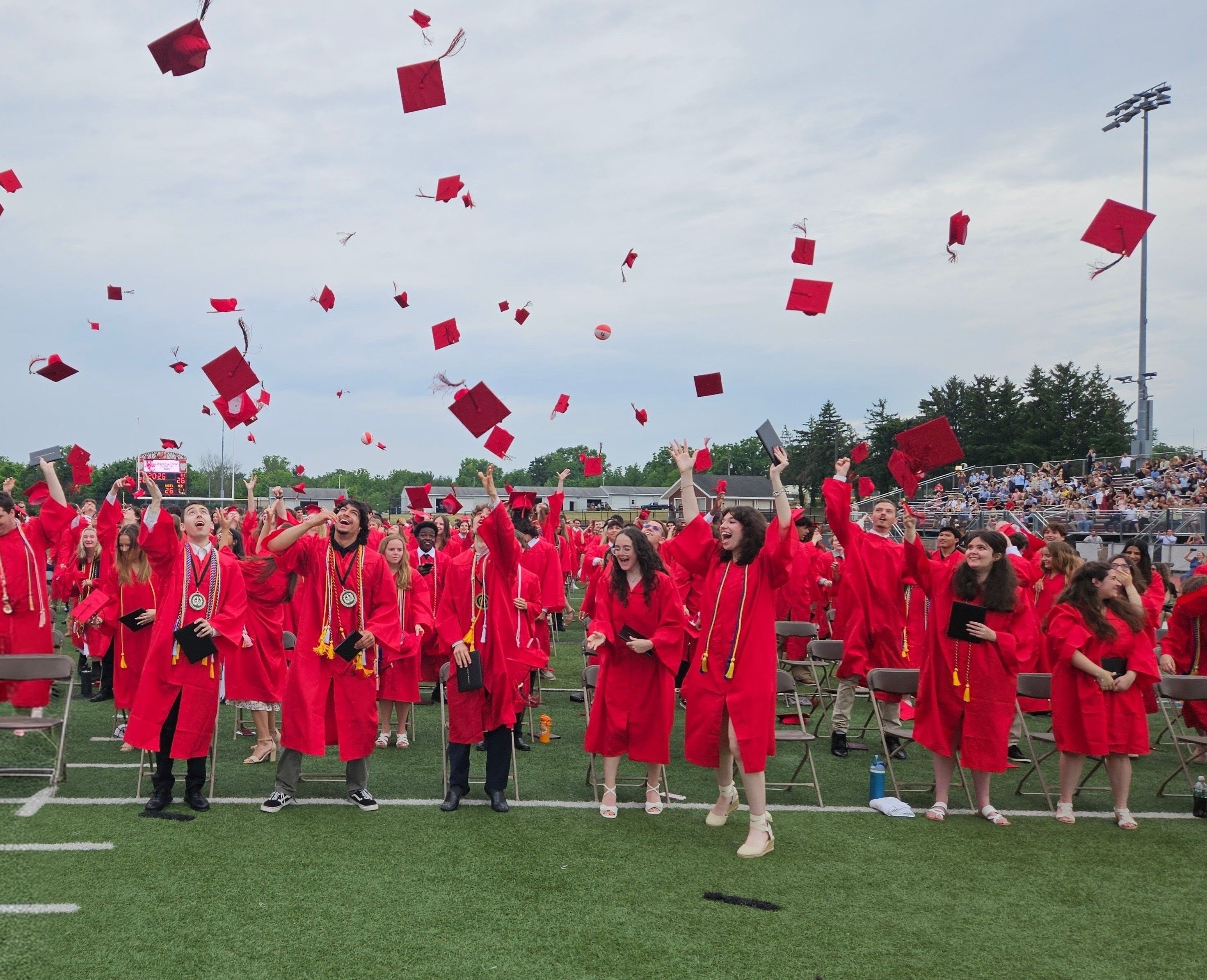 photo of students in red gowns throwing caps in the air at graduation
