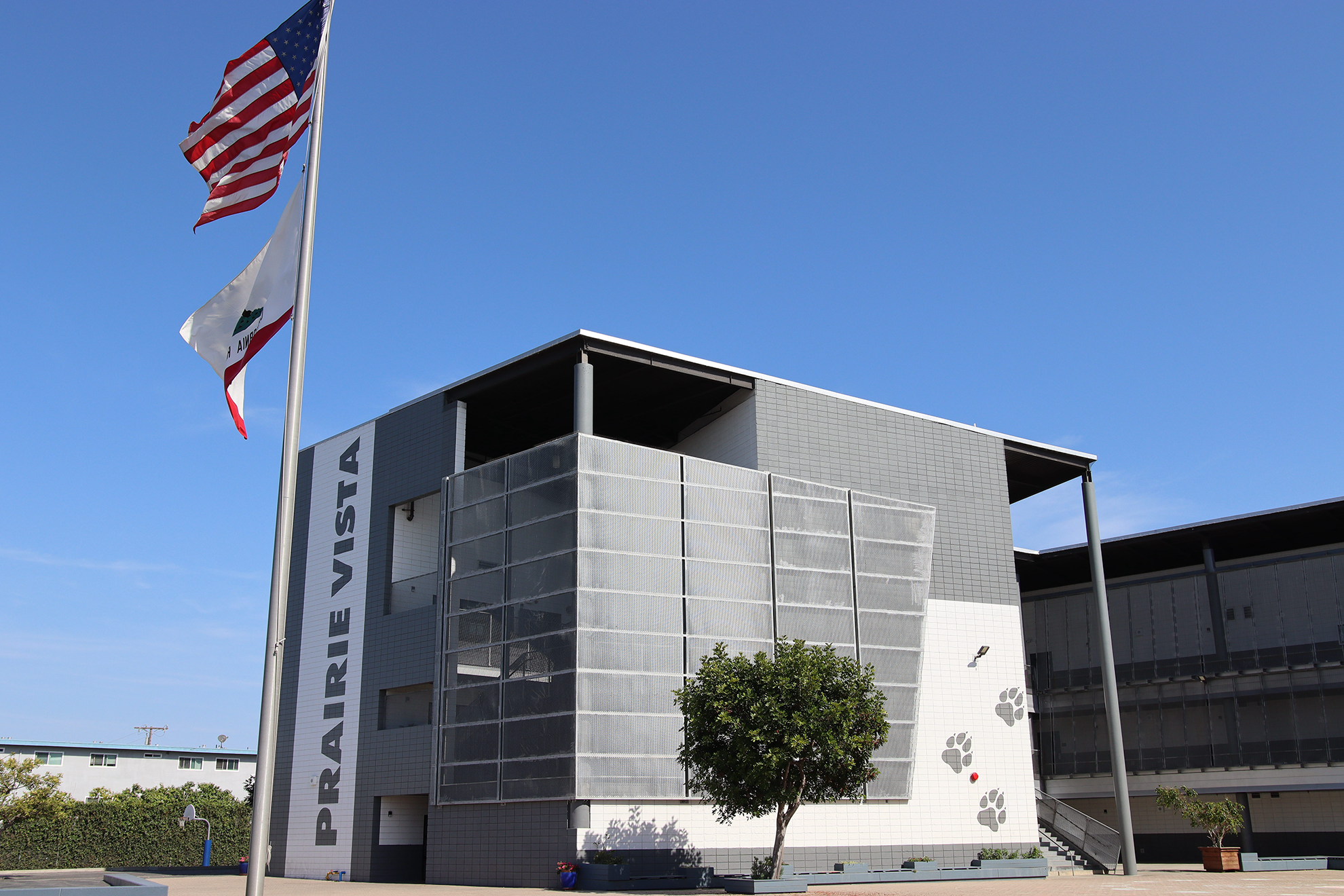 Exterior view of Prairie Vista Middle School campus with the U.S. and California flags flying in front of a modern two-story school building on a clear blue day.
