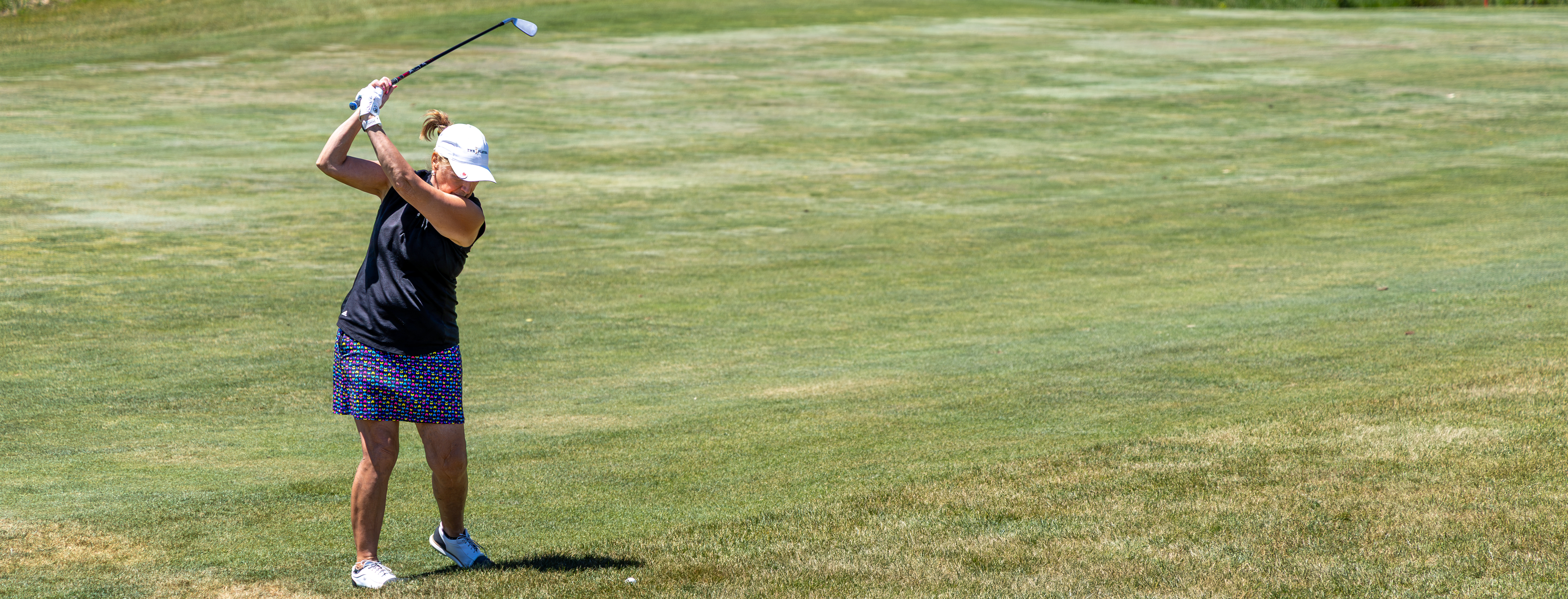 A woman pulls her golf club before making her swing.
