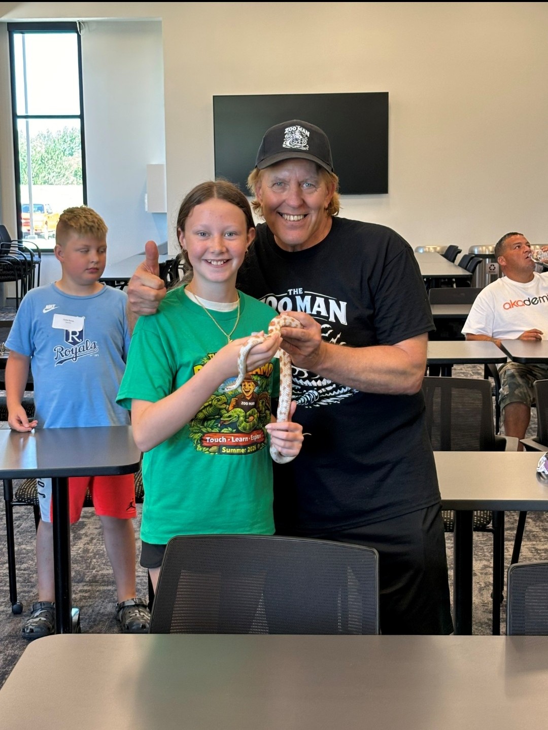 Zoo Man and young girl smiling at camera holding a snake