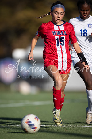 A young woman in a red and white soccer uniform dribbles a ball on a green field, with another player in a white uniform visible in the blurred background.