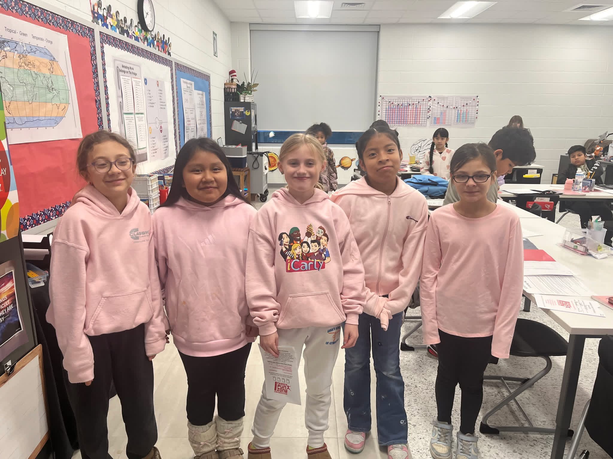 A group of girls all wearing pink smile at the camera.