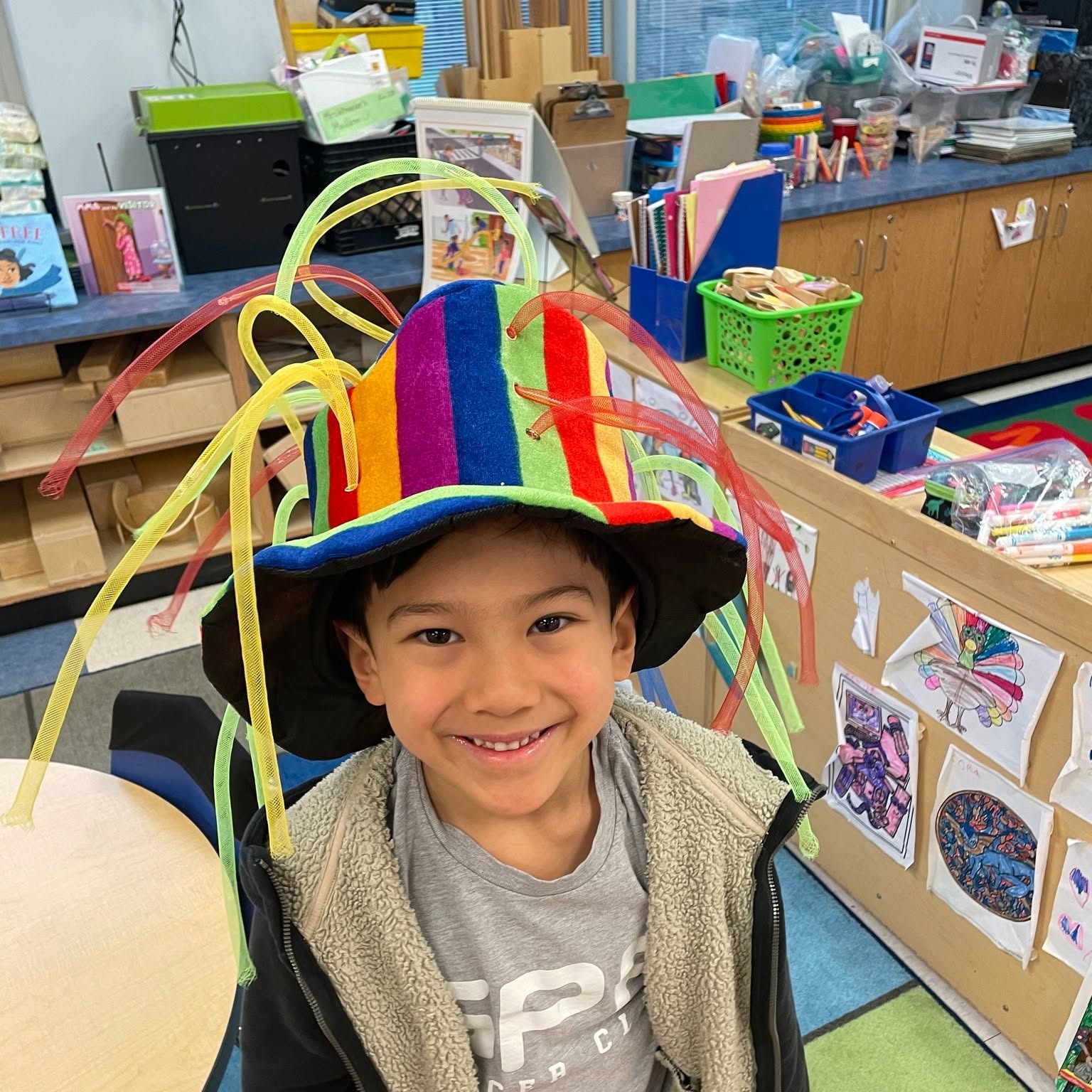 A kindergarten student wearing a brightly colored hat in class