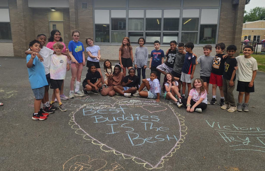 Students gather around a chalk mural stating Best Buddies is the Best.